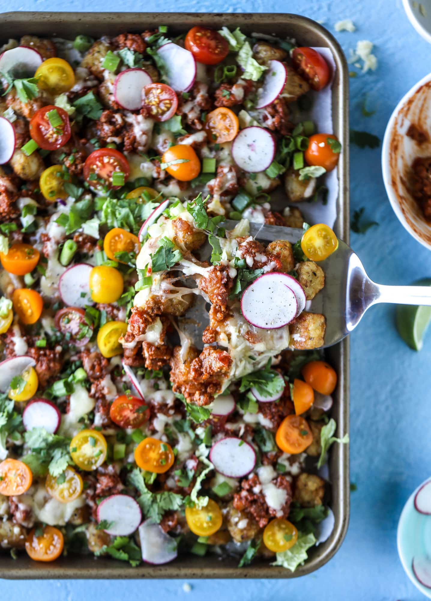 These tater tot nachos, otherwise known as totchos, are so delicious! They are cheesy and topped with a tangy, homemade sloppy joe mixture. Melted cheese, fresh tomatoes, scallions and chives come together for the best party food. I howsweeteats.com #totchos #tater #tot #nachos #sloppy #joes