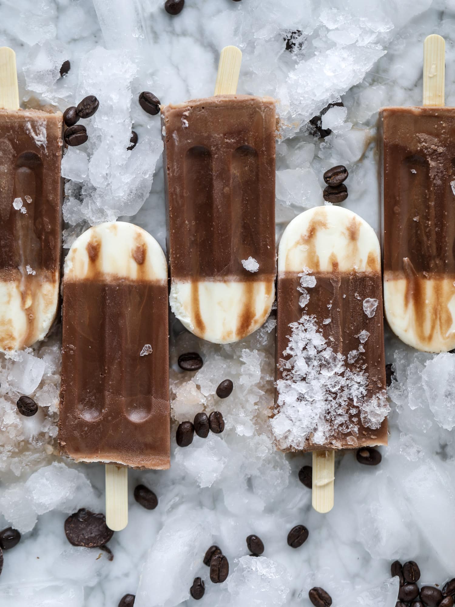 These fudgesicles are made with cold brew and dutch process cocoa for the most fun grown-up popsicle that can also deliver a little caffeine jolt. Topped with vanilla bean sweet cream, these are just like an iced latte in a pop! Serve as a treat or a snack! I howsweeteats.com #coldbrew #coffee #sweet #cream #popsicle #fudgesicle