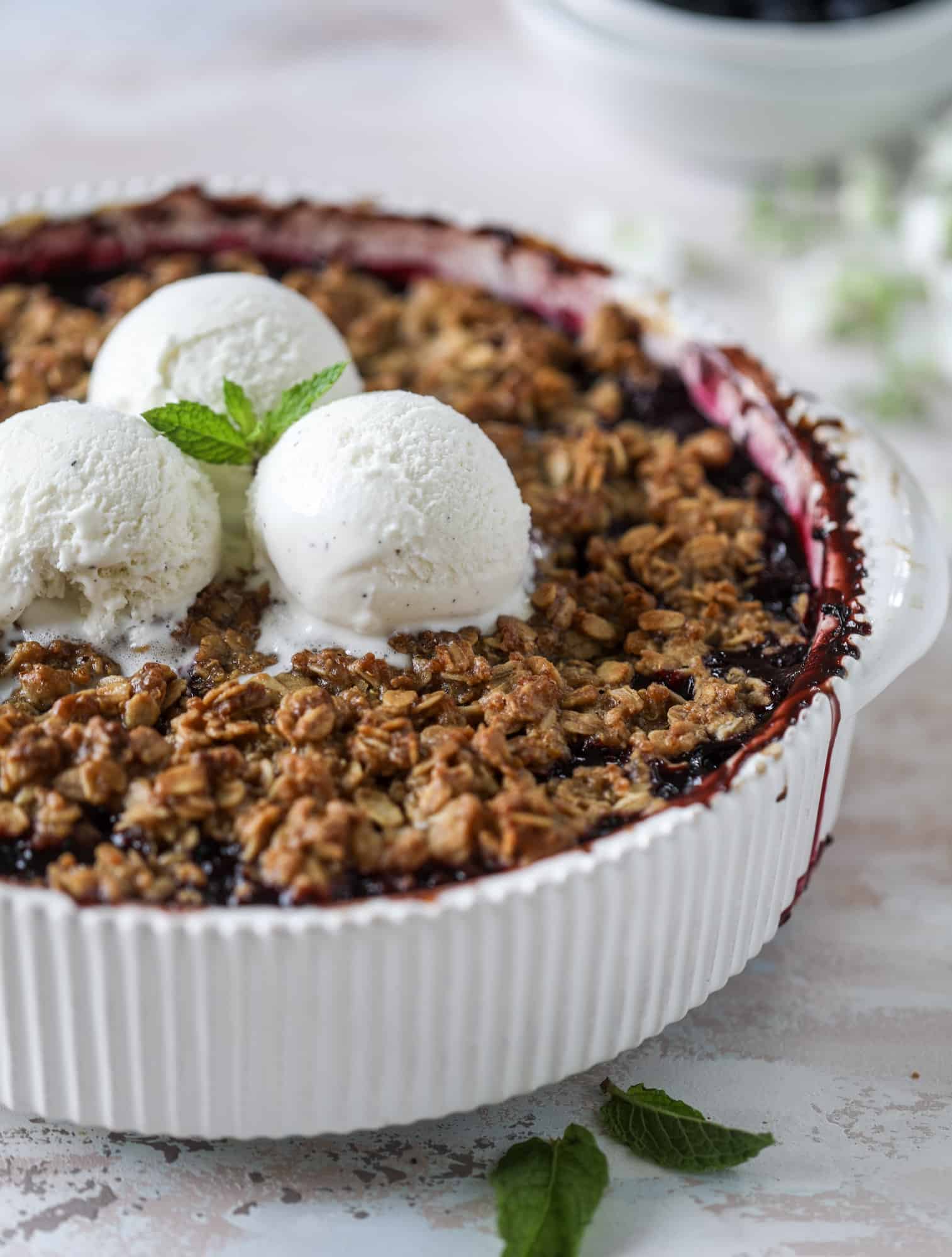 This blueberry crisp is warm and bursting with sweet and juicy fruit. It's topped with a quinoa oatmeal brown sugar topping and is the perfect dessert for summer. Served warm and topped with vanilla ice cream, it's just divine! I howsweeteats.com #blueberry #crisp #quinoa #oats #dessert #fruit 