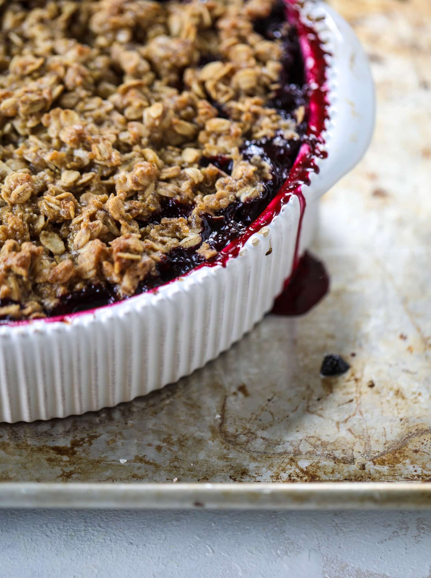 This blueberry crisp is warm and bursting with sweet and juicy fruit. It's topped with a quinoa oatmeal brown sugar topping and is the perfect dessert for summer. Served warm and topped with vanilla ice cream, it's just divine! I howsweeteats.com #blueberry #crisp #quinoa #oats #dessert #fruit 