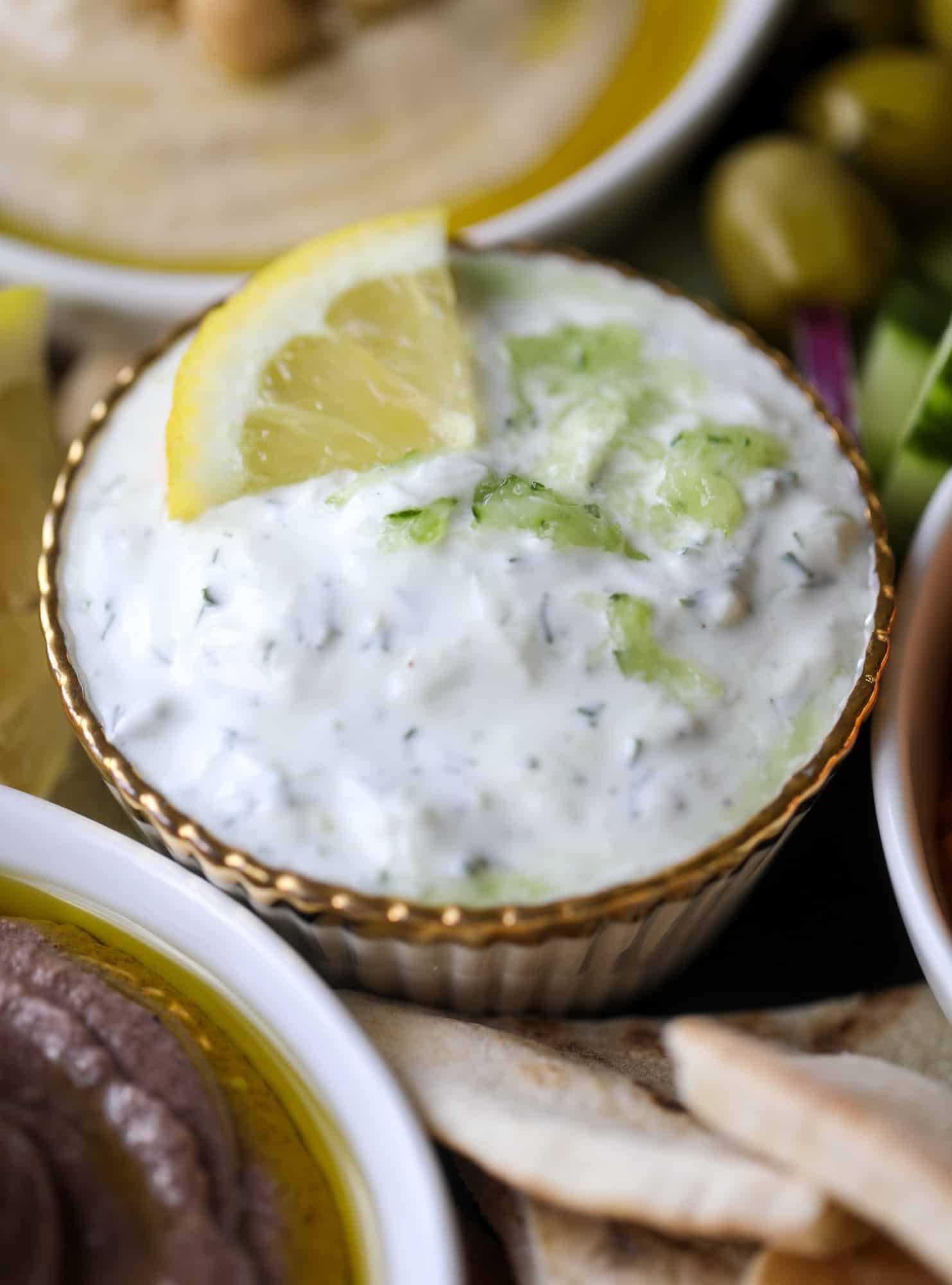 Here you can find out how to make the perfect hummus platter! This trio includes caramelized onion hummus, smoky black bean hummus and roasted red pepper white bean hummus, along with a couscous salad and quick tzatziki! I howsweeteats.com #hummus #platter #appetizer #snack #chickpeas #healthy #blackbeans #yogurt #tzatziki