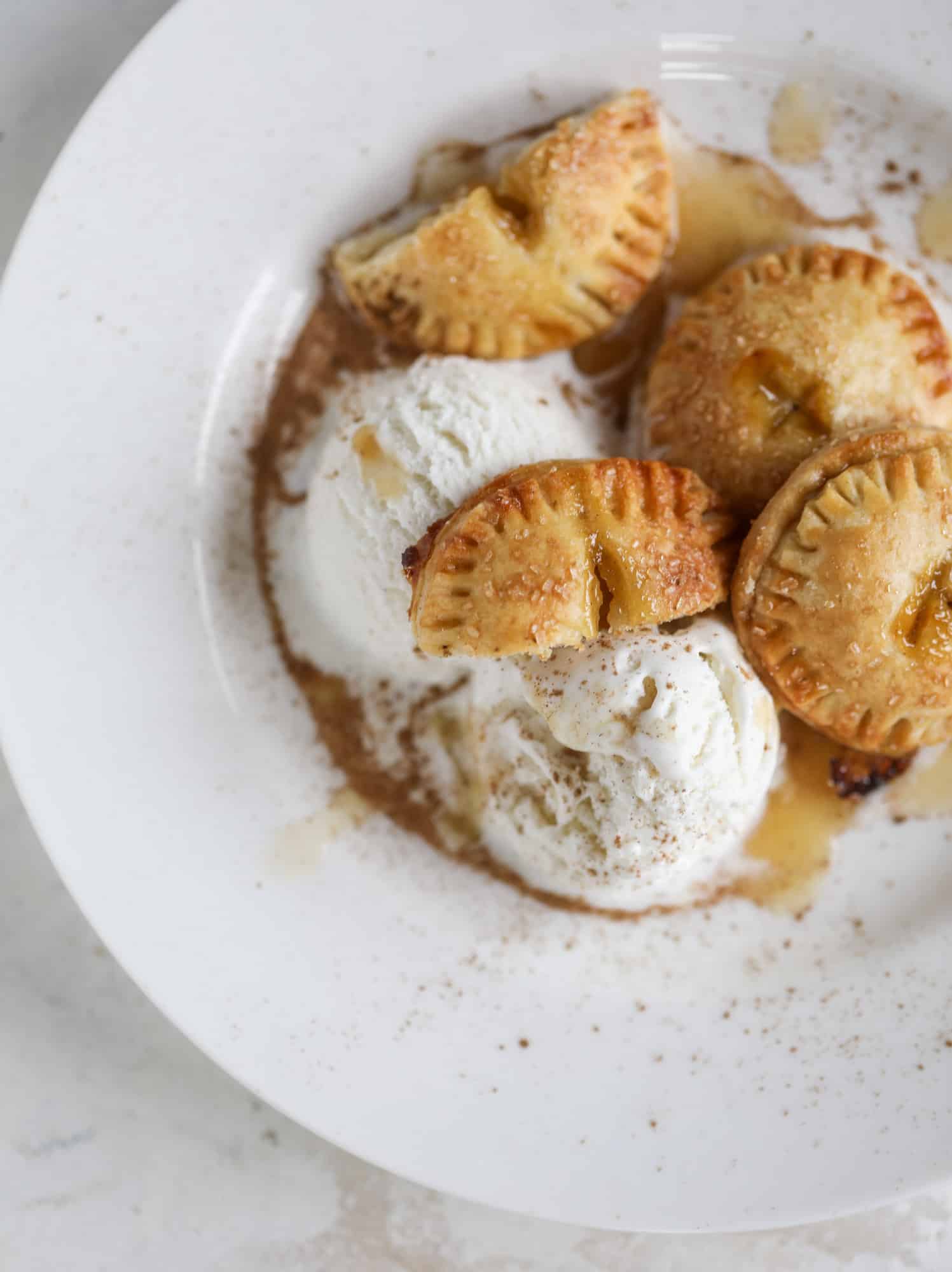 These little peach hand pies are super easy to make and oh-so delicious for summer! A warm and syrupy homemade peach filling made with brown sugar and bourbon, stuck inside a flakey all-butter crust and sprinkled with coarse sugar. SO GOOD. I howsweeteats.com #peach #hand #pies #mini #dessert #summer