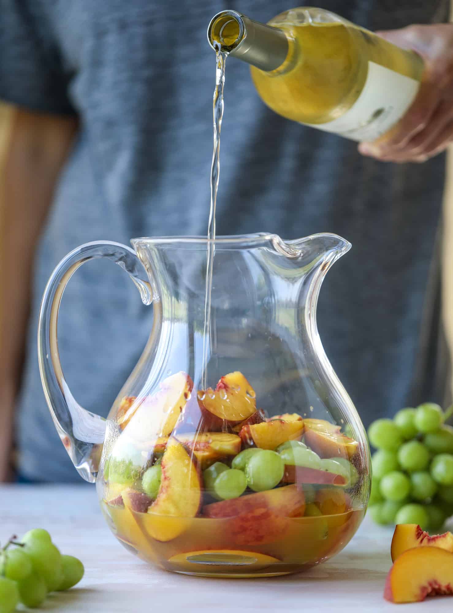 This pinot grigio sangria is absolutely perfect for summer, complete with peach nectar, fresh and frozen peach slices, brandy and bubbles! Frozen green grapes add some chill without watering down the drink. It's perfect! I howsweeteats.com #pinot #grigio #peach #sangria #cocktails #punch #summer #wine