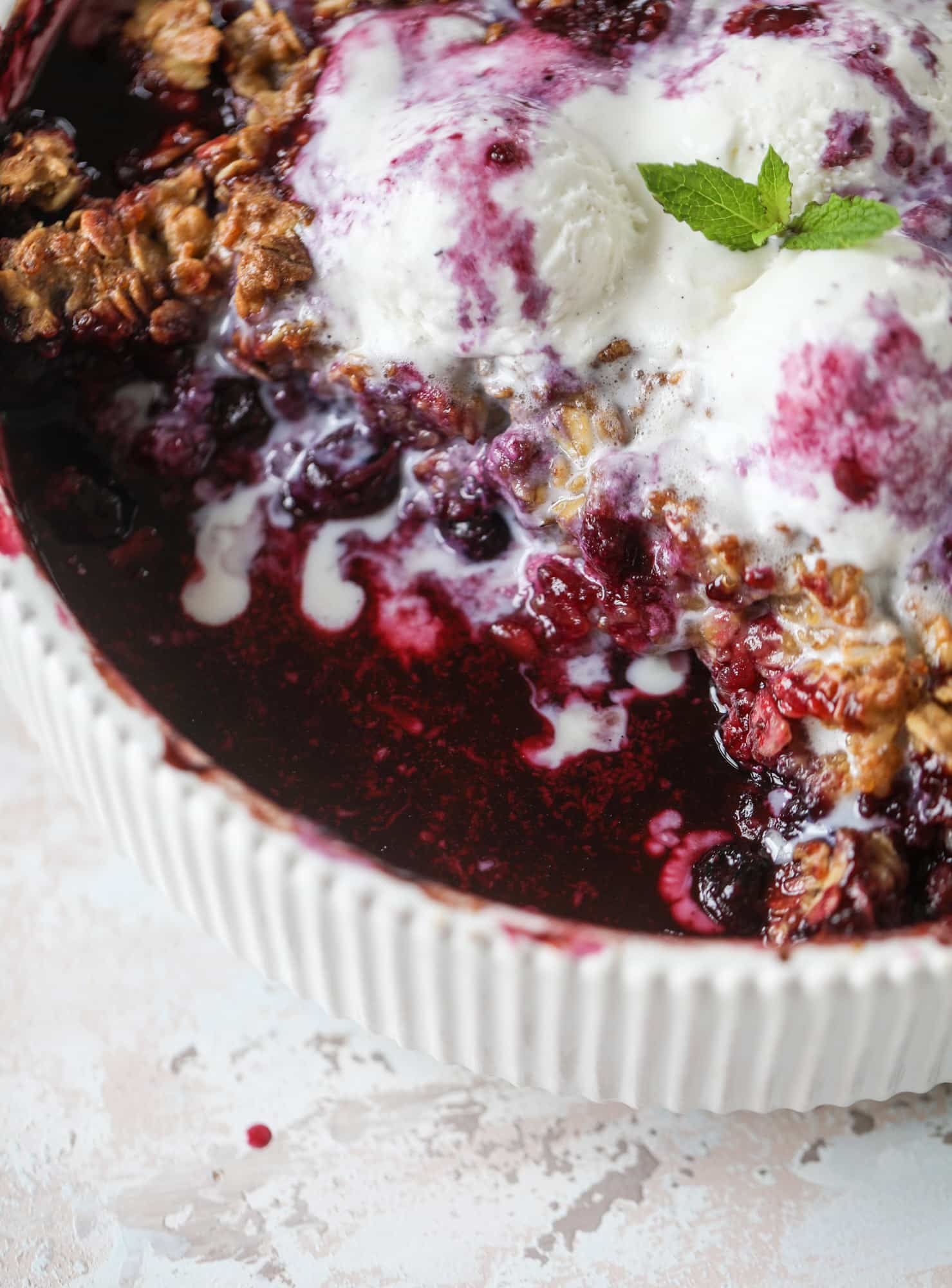 This blueberry crisp is warm and bursting with sweet and juicy fruit. It's topped with a quinoa oatmeal brown sugar topping and is the perfect dessert for summer. Served warm and topped with vanilla ice cream, it's just divine! I howsweeteats.com #blueberry #crisp #quinoa #oats #dessert #fruit 