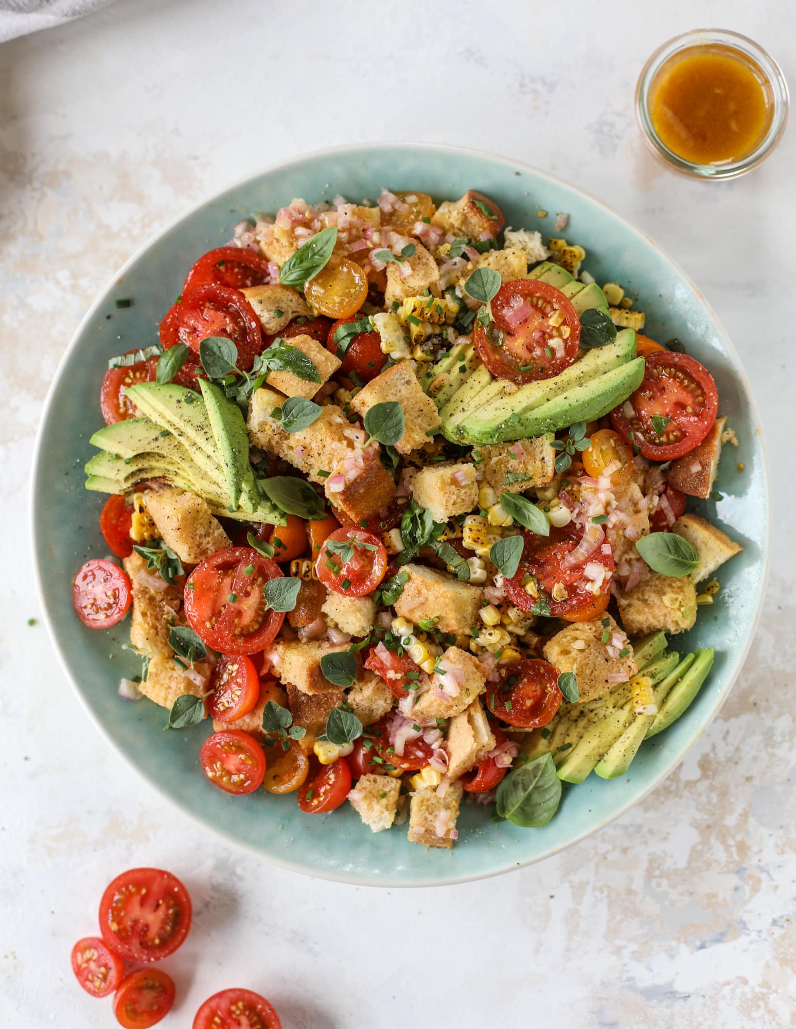 This is the perfect tomato panzanella salad! It's full of juicy, bursting, sweet tomatoes, toasted sourdough bread cubes, fresh herbs, grilled corn, sliced avocado and an incredible homemade dressing that blankets everything in deliciousness. SO good. I howsweeteats.com #panzanella #salad #tomato #basil #summer #corn #avocado #healthy #recipes