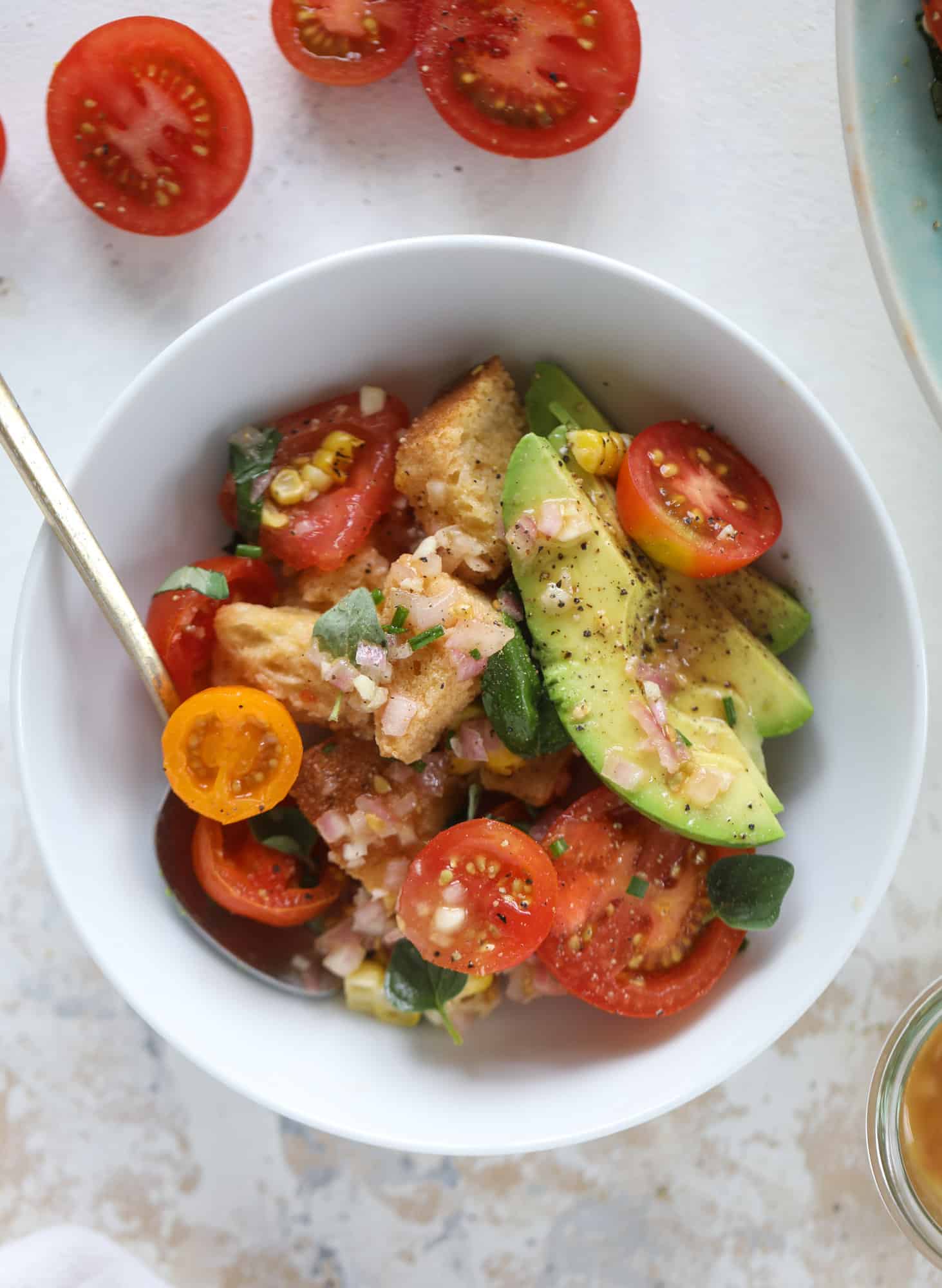This is the perfect tomato panzanella salad! It's full of juicy, bursting, sweet tomatoes, toasted sourdough bread cubes, fresh herbs, grilled corn, sliced avocado and an incredible homemade dressing that blankets everything in deliciousness. SO good. I howsweeteats.com #panzanella #salad #tomato #basil #summer #corn #avocado #healthy #recipes