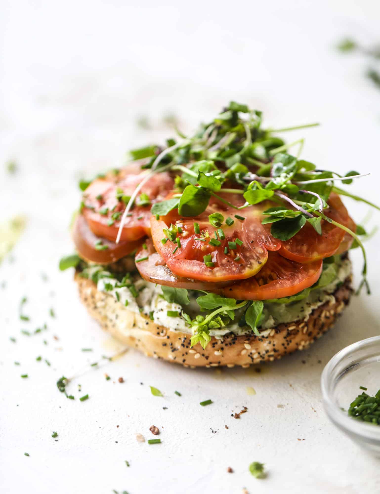 These avocado tomato sandwiches are the perfect lunch! Complete with veggie cream cheese, smoked sea salt, fresh chives and microgreens, the sliced avocado and heirloom tomatoes are sandwiched on an everything bagel for a flavor explosion. I howsweeteats.com #avocado #tomato #sandwich #healthy #lunch