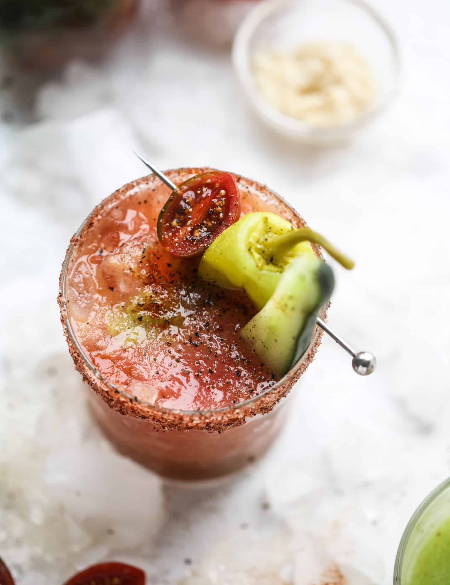 This bloody mary recipe is made with fresh heirloom tomatoes - the gems of summer! The colors swirl together to create a stunning drinking that is loaded with smoky, spicy flavor. Top with your favorite snacks foe the perfect brunch! I howsweeteats.com #bloody #mary #recipe #best #heirloom #tomatoes #cocktail
