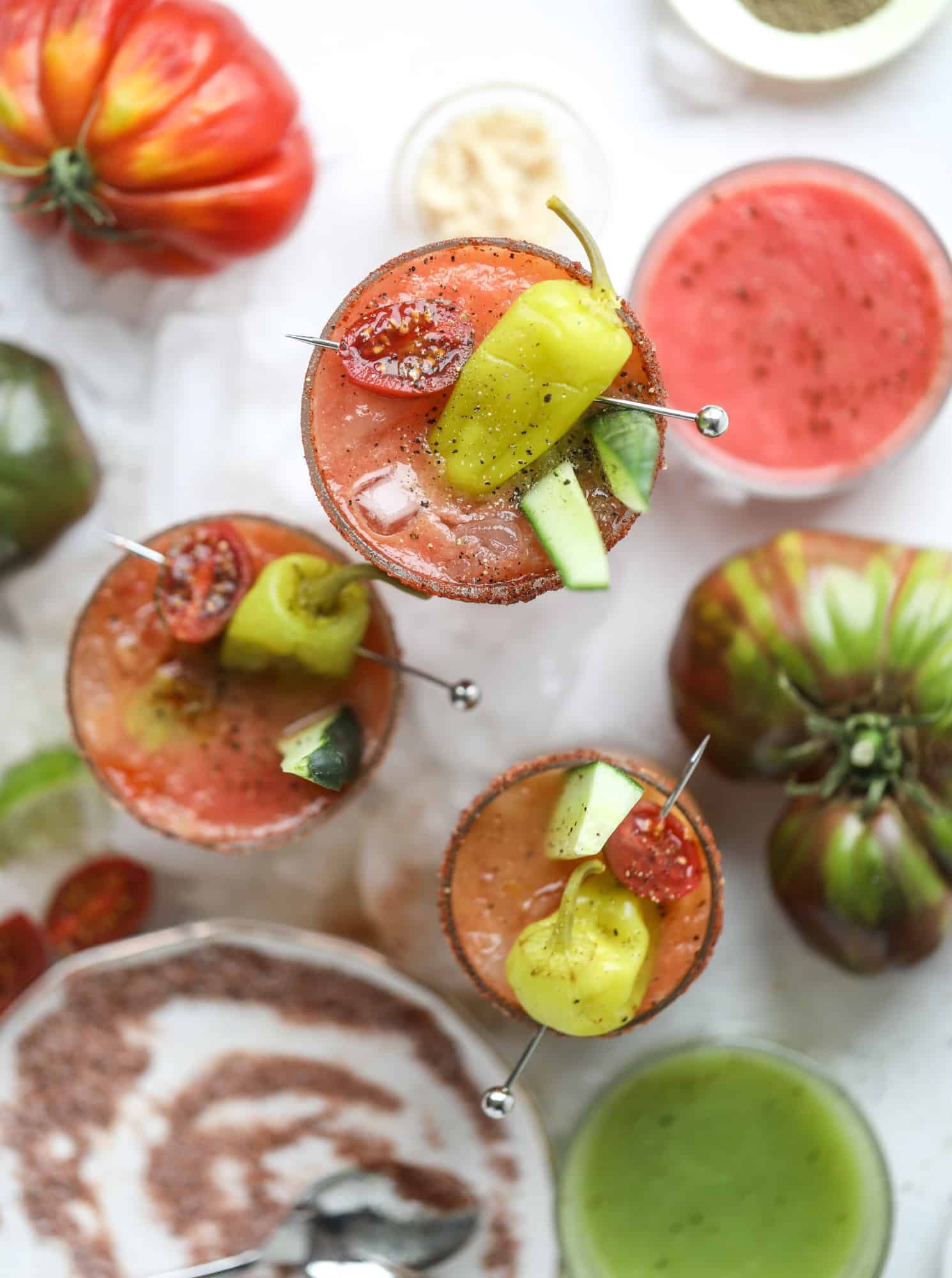 This bloody mary recipe is made with fresh heirloom tomatoes - the gems of summer! The colors swirl together to create a stunning drinking that is loaded with smoky, spicy flavor. Top with your favorite snacks foe the perfect brunch! I howsweeteats.com #bloody #mary #recipe #best #heirloom #tomatoes #cocktail