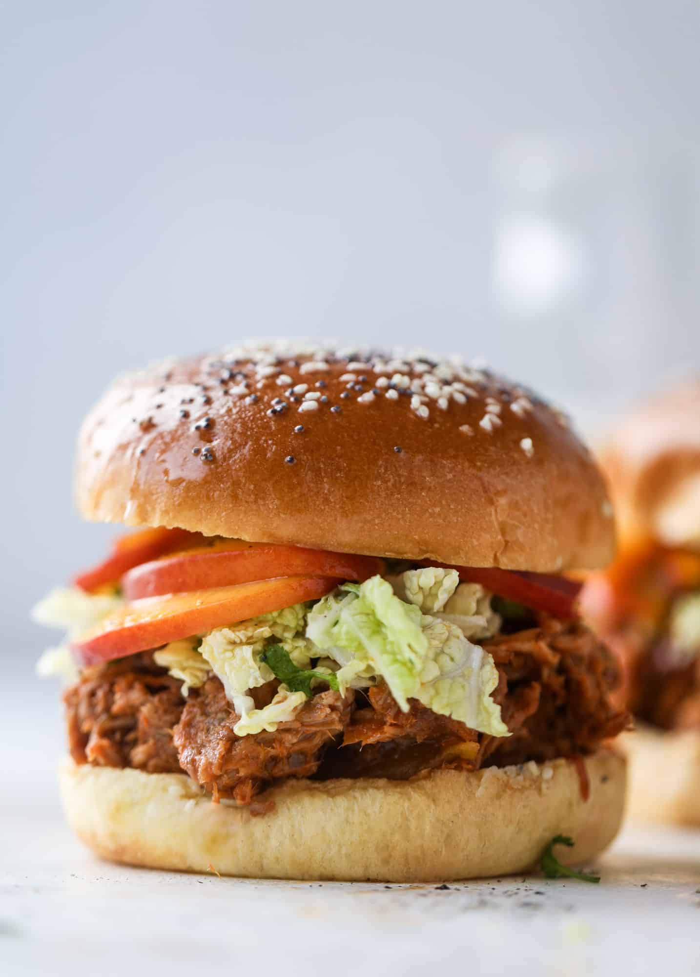 This chipotle pulled pork sandwich is spicy, sweet and saucy. Throw it on a bun or a plate and top it with the most delicious quick pickled peaches and napa cabbage slaw. Flavor and texture make this sandwich incredible! I howsweeteats.com #pulled #pork #chipotle #pickled #peaches #slaw #sandwiches #slow #cooker