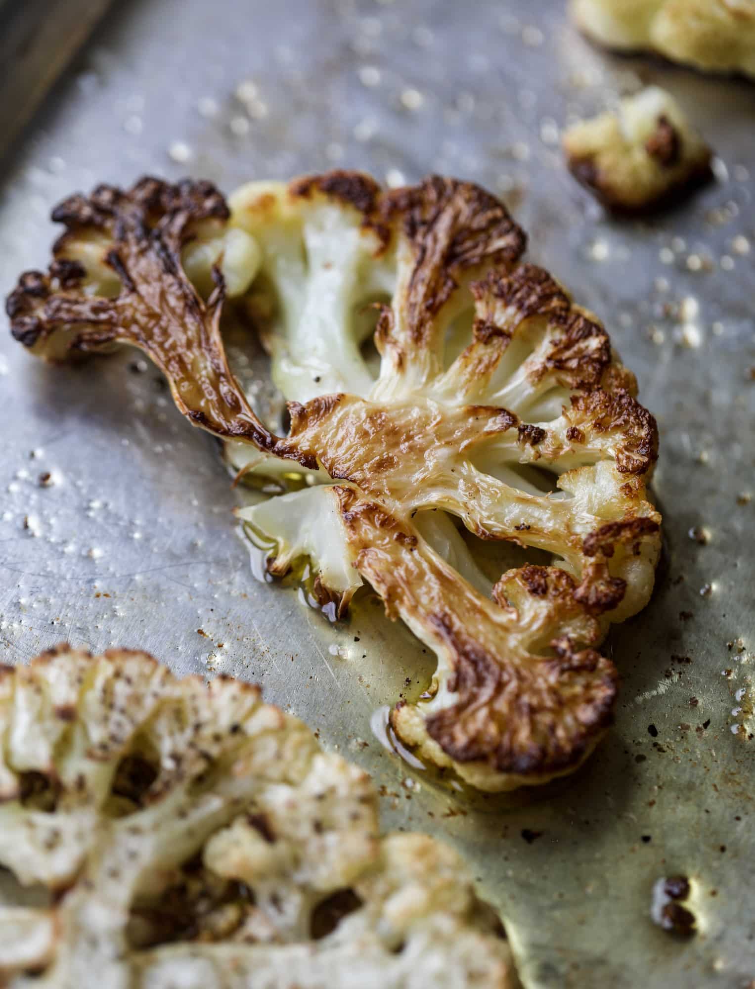 This roasted cauliflower with hummus, olives and feta is super flavorful and a wonderful meal, side dish or snack. Flavorful roasted cauliflower, creamy hummus, briney olives and tangy feta come together to make a major taste explosion. I howsweeteats.com #roasted #cauliflower #hummus #olives #feta