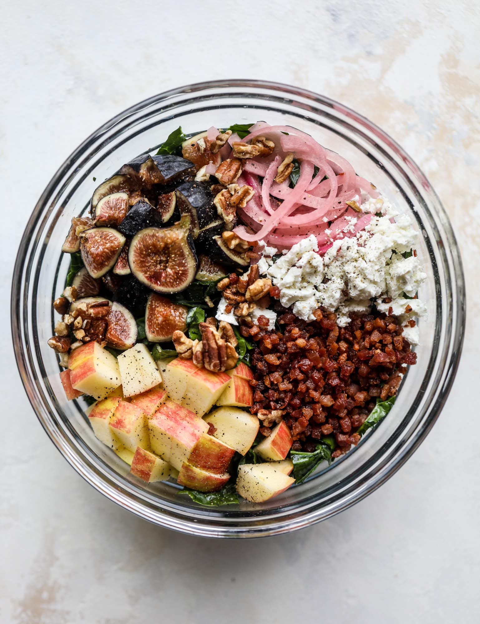 This fall kale salad is perfect for the season and full of so much delicious flavor! Shredded kale, honeycrisp apple, fresh figs, pancetta, pickled onions, pecans and goat cheese come together with a maple cider vinaigrette for salad heaven. I howsweeteats.com #fall #kale #salad #apples #figs #pecans