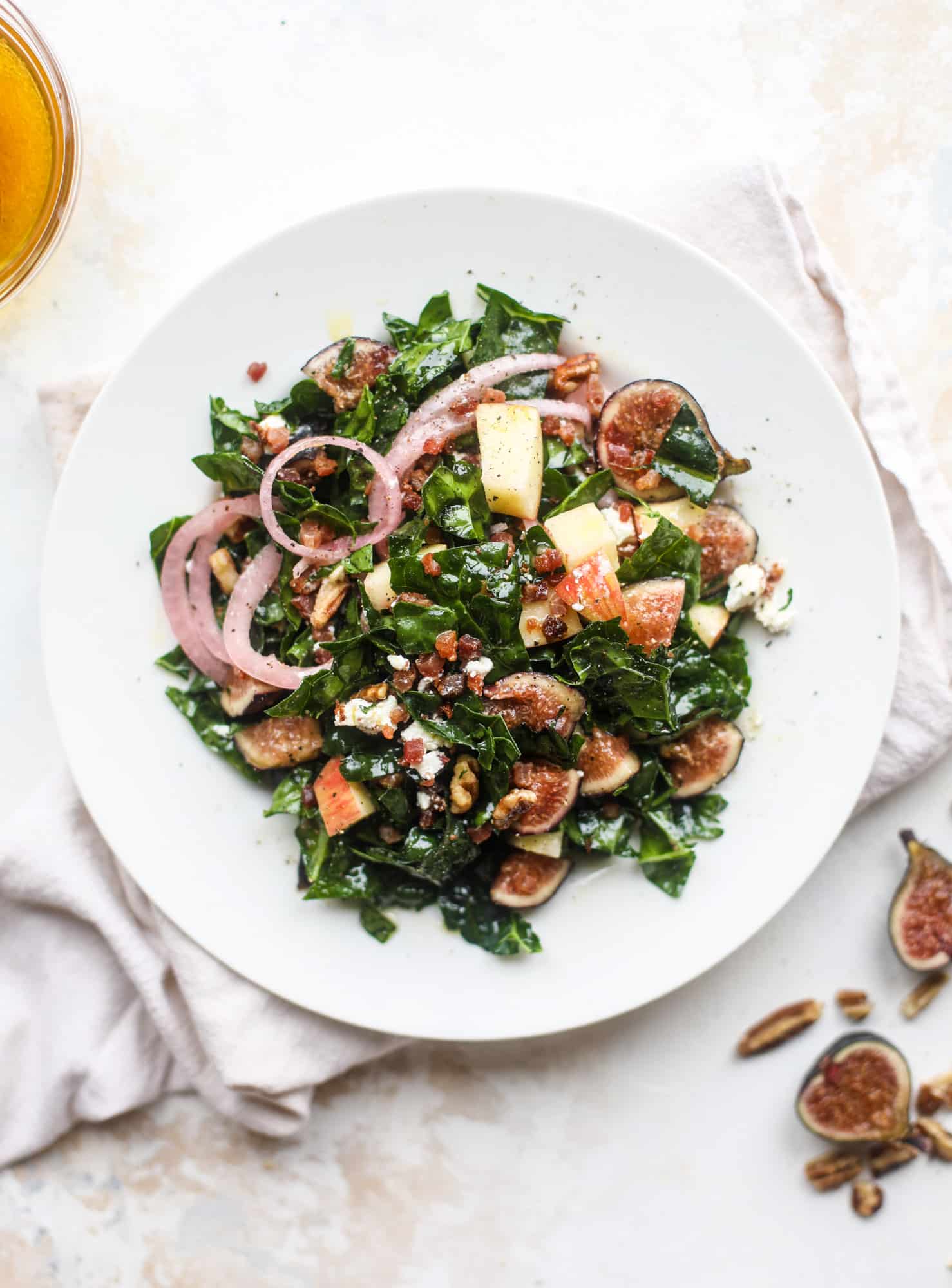This fall kale salad is perfect for the season and full of so much delicious flavor! Shredded kale, honeycrisp apple, fresh figs, pancetta, pickled onions, pecans and goat cheese come together with a maple cider vinaigrette for salad heaven. I howsweeteats.com #fall #kale #salad #apples #figs #pecans