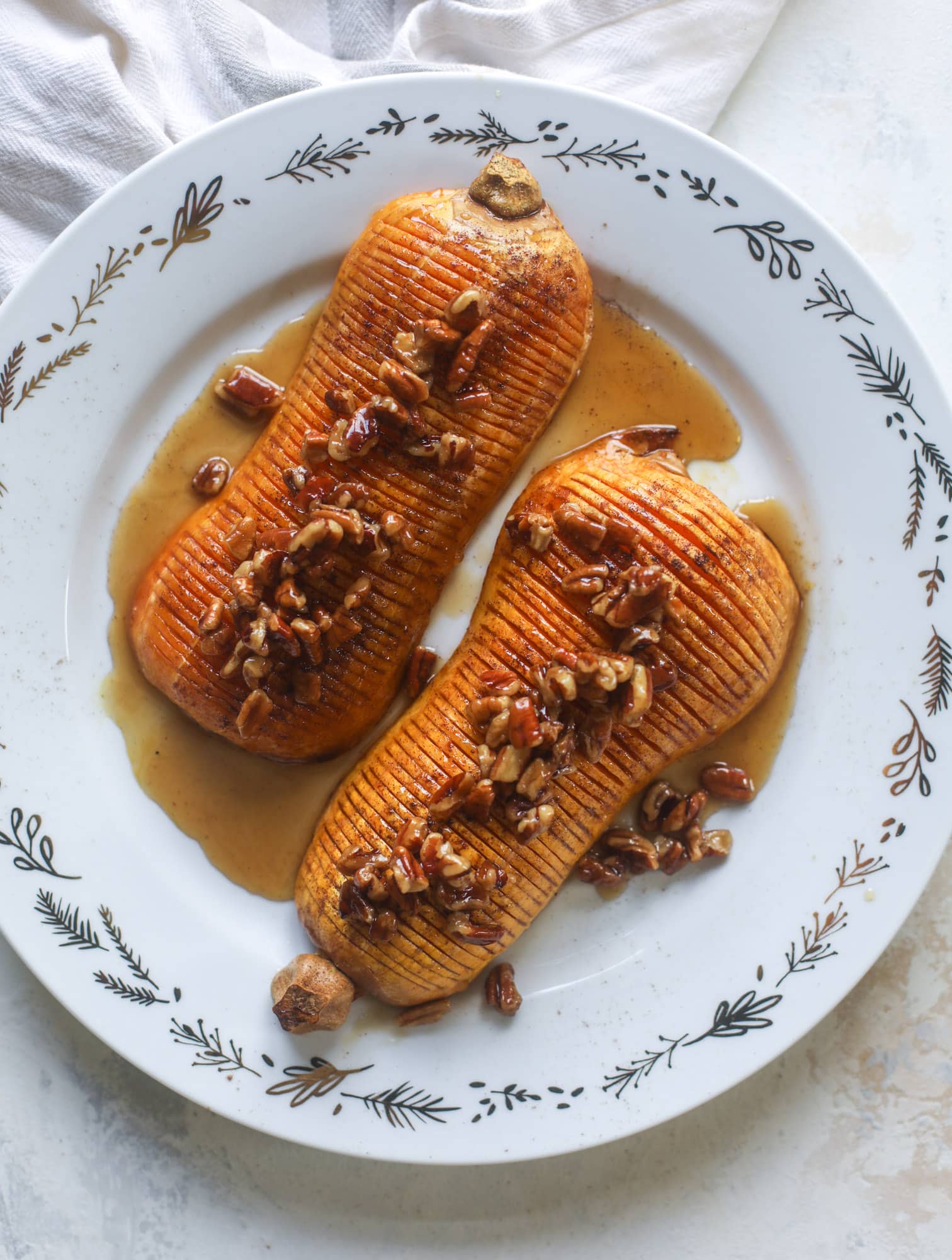 This hasselback butternut squash is perfect for Thanksgiving - and you can easily make it two ways! We have a maple pecan hassleback butternut squash and a brown butter sage hasselback butternut squash. Delicious! I howsweeteats.com #hasselback #butternutsquash