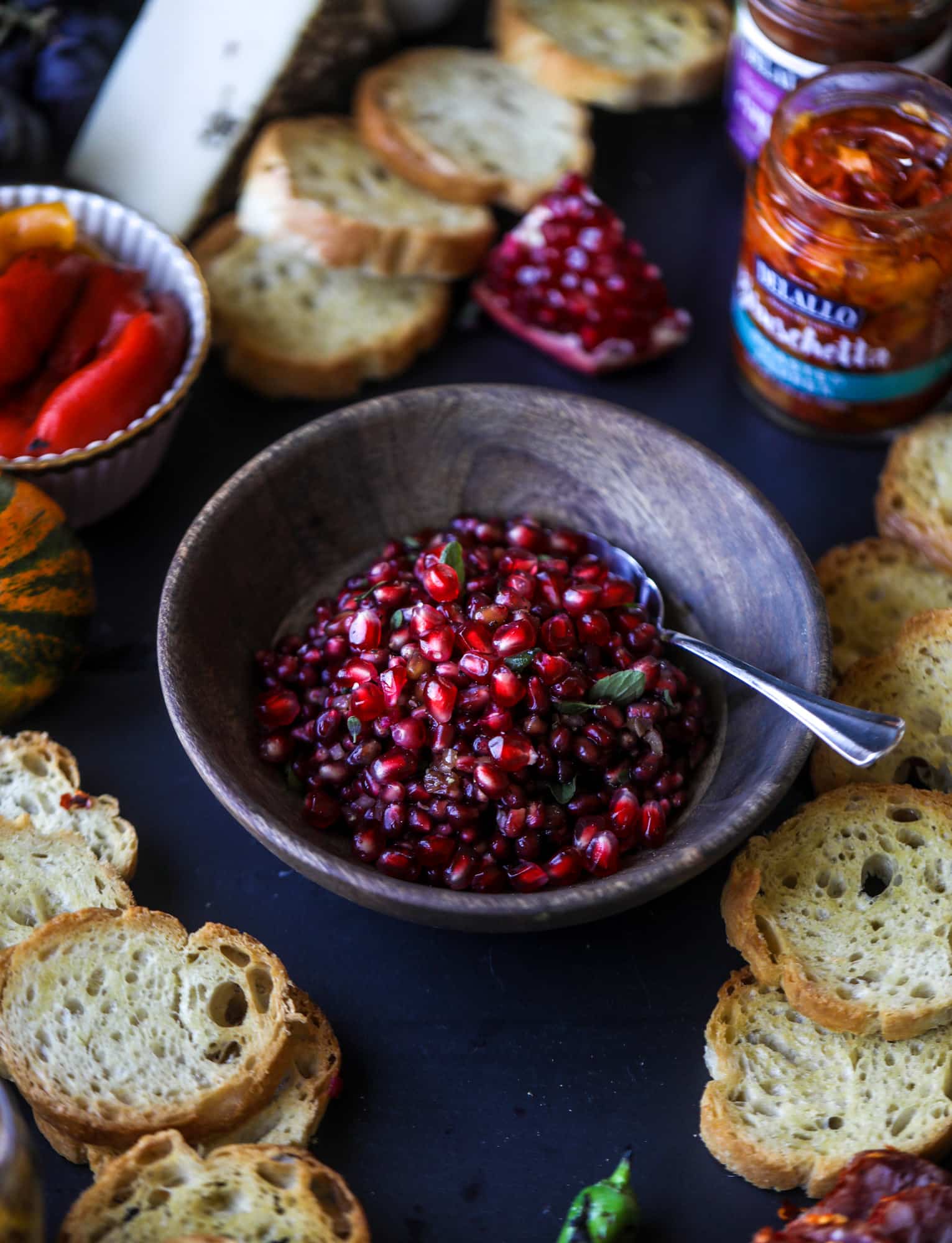 This is the perfect autumn harvest bruschetta board to feed a crowd or serve at a party! The standout is pomegranate relish with a cinnamon shallot vinaigrette, lots of toasty bread, bruschettas, cheese and olives. Everything that's delish! I howsweeteats.com #bruschetta #board