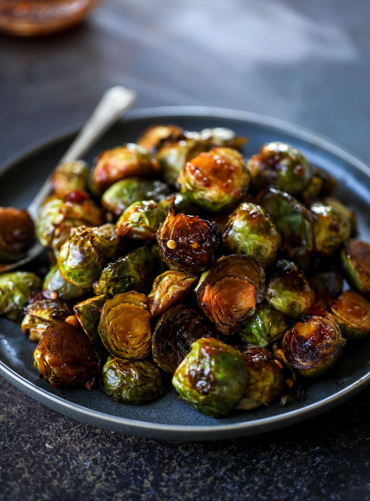These sweet and spicy brussels sprouts are roasted to perfect and the most delicious side dish! It's a great way to elevate regular old brussels sprouts and make a fantastic side to to serve on a weeknight! I howsweeteats.com #spicy #brusselssprouts
