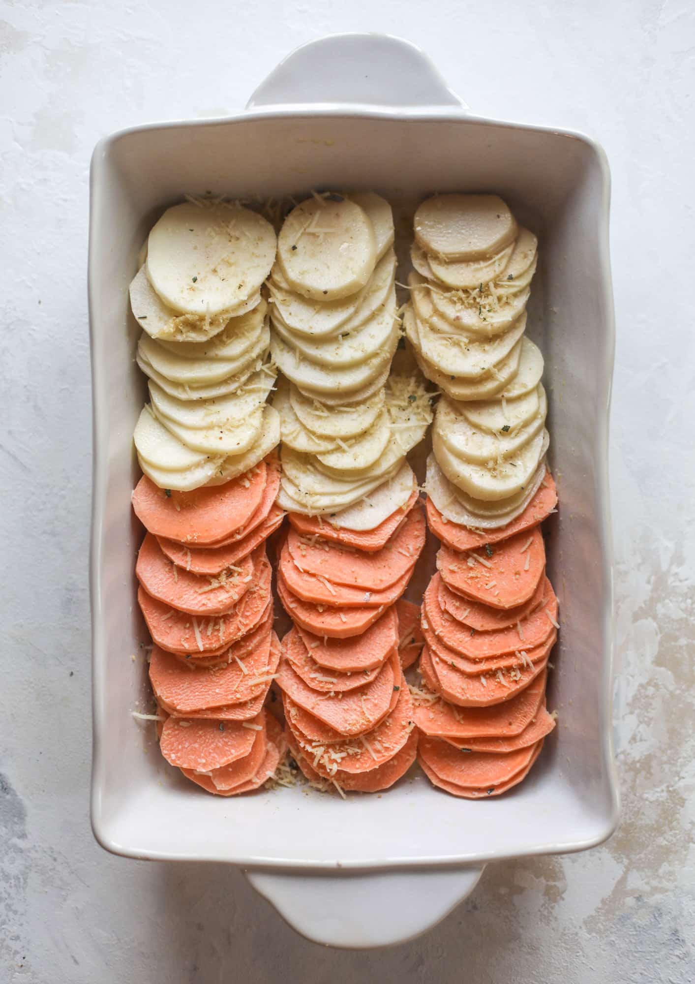 These scalloped potatoes are a cheese lover's dream. Sharp asiago and cream envelops idaho and sweet potatoes in these scalloped potatoes to please everyone! The crunchy asiago topping is irresistible. I howsweeteats.com #scalloped #potatoes