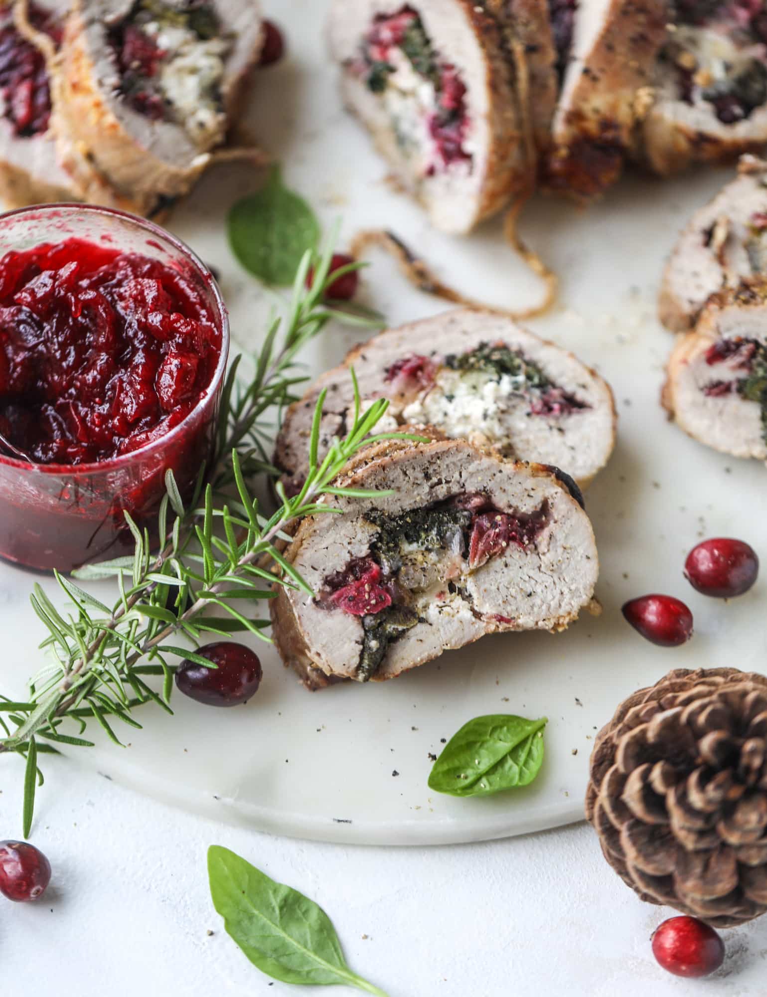 This holiday stuffed pork tenderloin is filled with caramelized onion, fresh cranberry sauce, goat cheese and fresh spinach. It's a show stopped and super delicious, along with being fairly simple to make! I howsweeteats.com #stuffed #porktenderloin