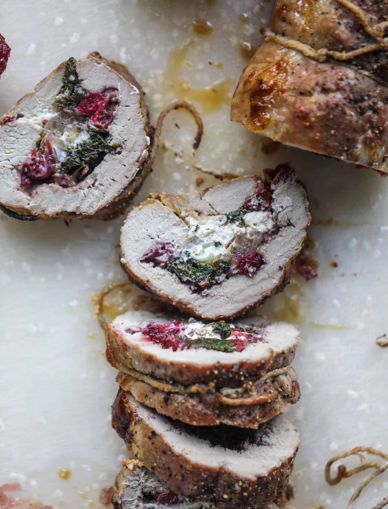 This holiday stuffed pork tenderloin is filled with caramelized onion, fresh cranberry sauce, goat cheese and fresh spinach. It's a show stopped and super delicious, along with being fairly simple to make! I howsweeteats.com #stuffed #porktenderloin