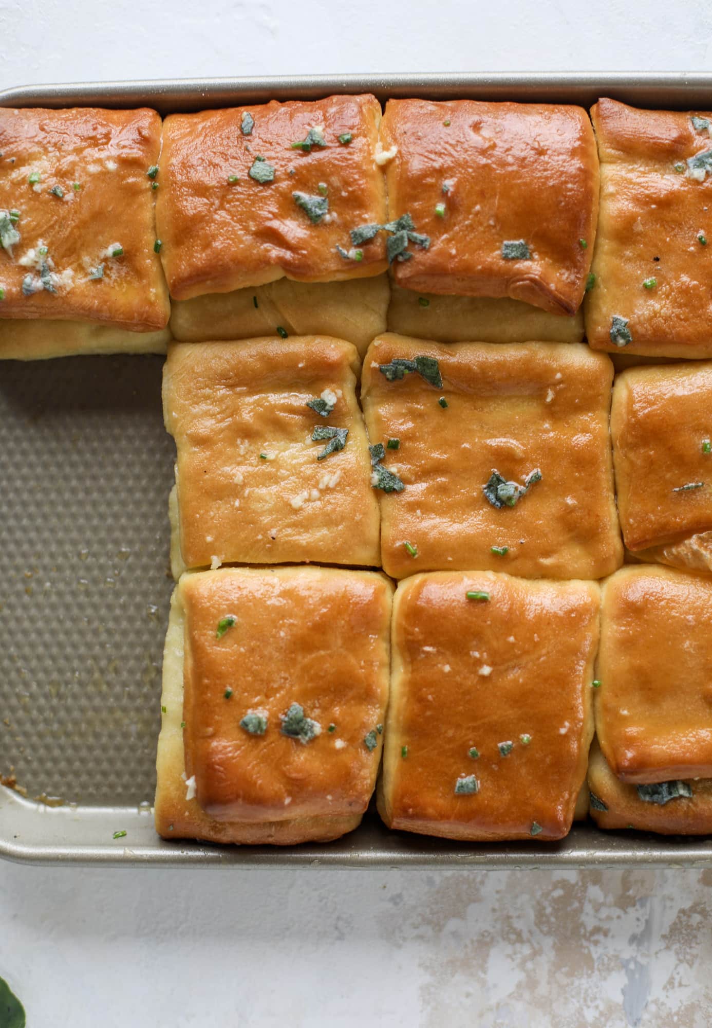 Garlic herb parker house rolls are full of incredibly buttery flavor! They are brushed with a garlic herb butter and are super fluffy, soft and tender. Perfect for Thanksgiving or the holidays and you can make the dough a bit ahead of time! I howsweeteats.com #parkerhouse #rolls