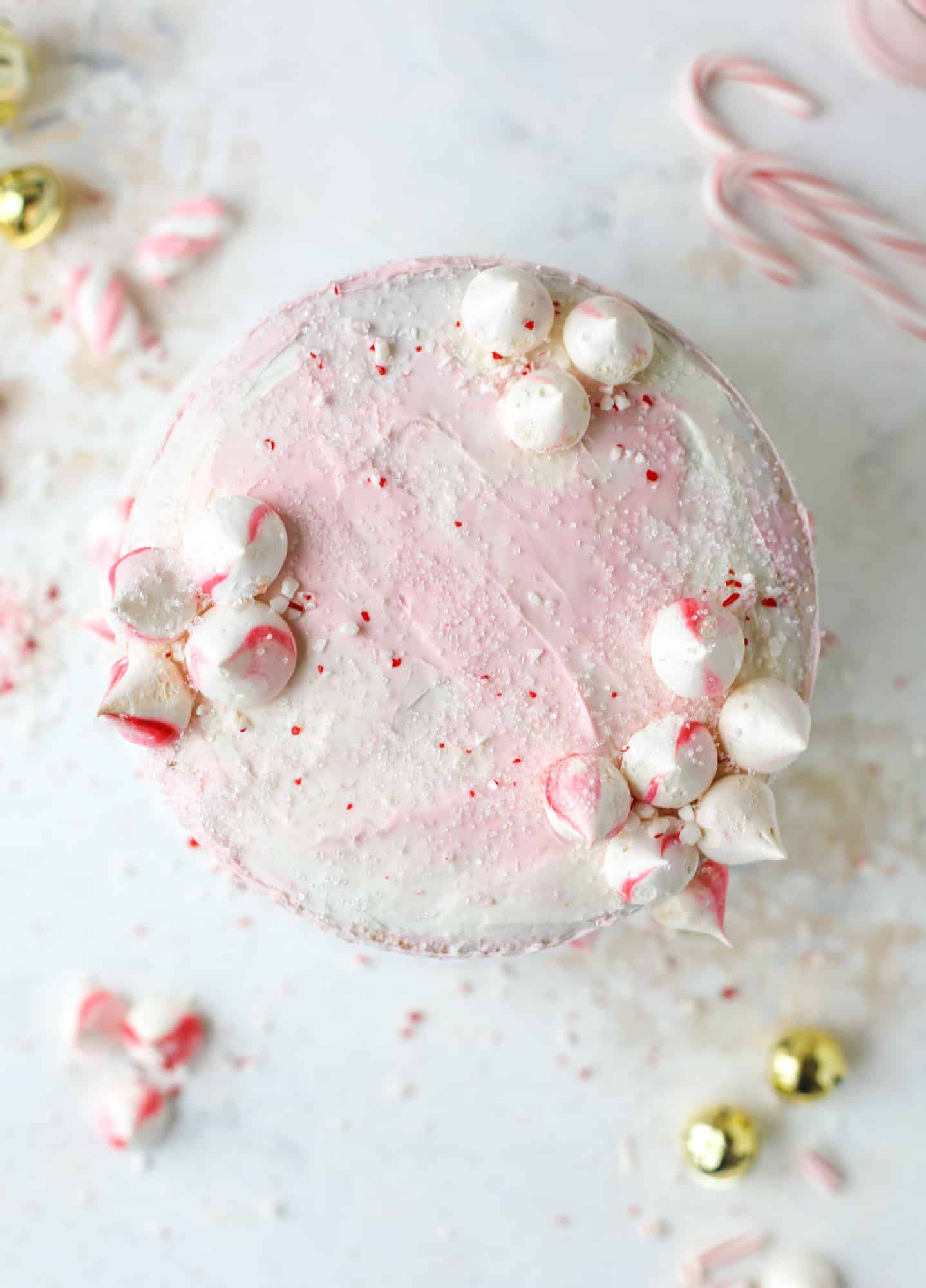 This pink peppermint cake is festive and delicious for the holidays! Layers of vanilla cake frosting with peppermint cream cheese frosting, covered in sparkly sugar and peppermint meringues. Couldn't be cuter! I #pinkpeppermint #cake
