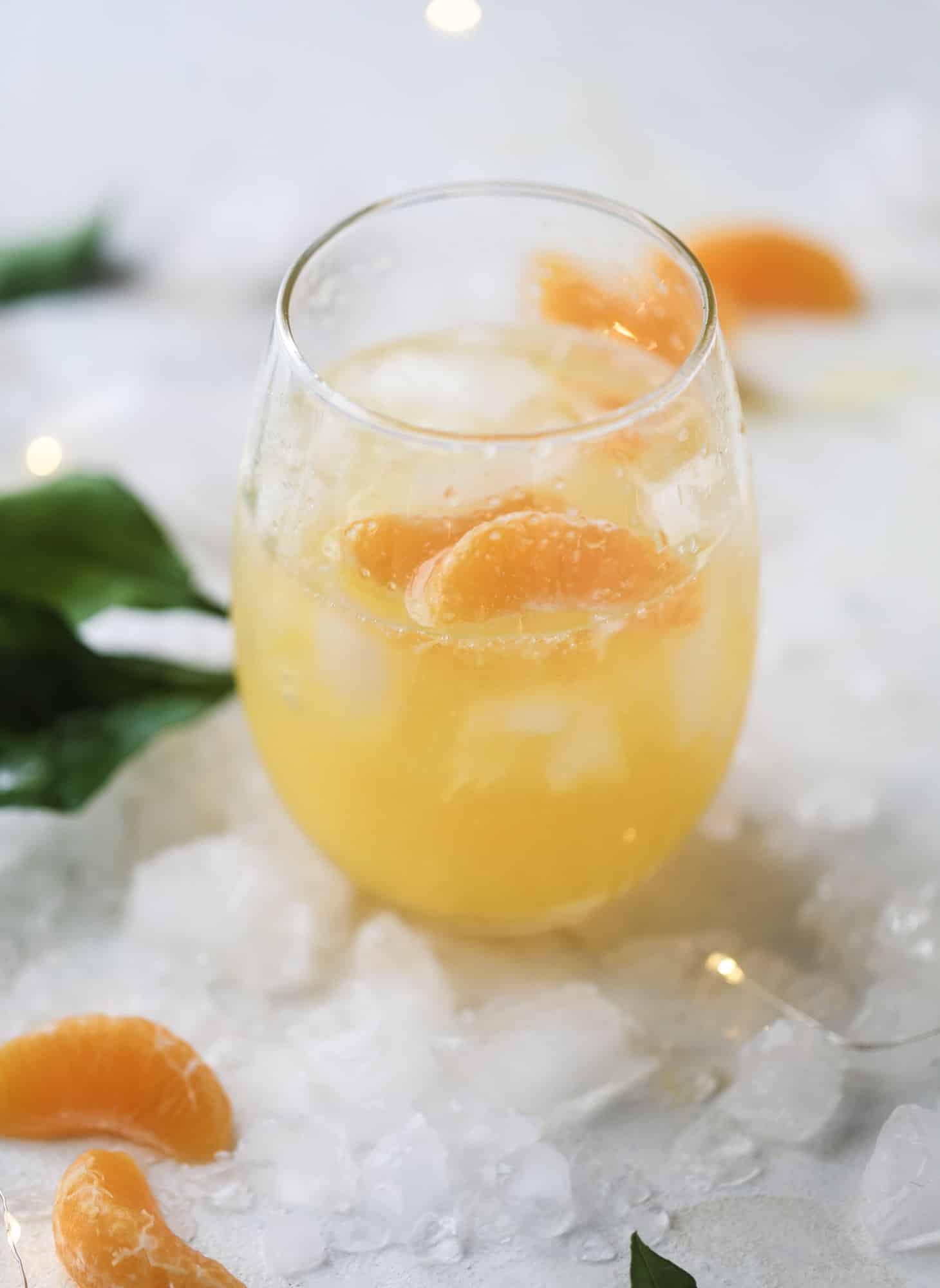 This satsuma cocktail is perfect for the holiday season and winter months when sweet satsumas are in season! This cocktail uses gin or vodka and is topped with champagne and garnished with a few satsuma wedges. Delicious! I howsweeteats.com #satsuma #cocktail