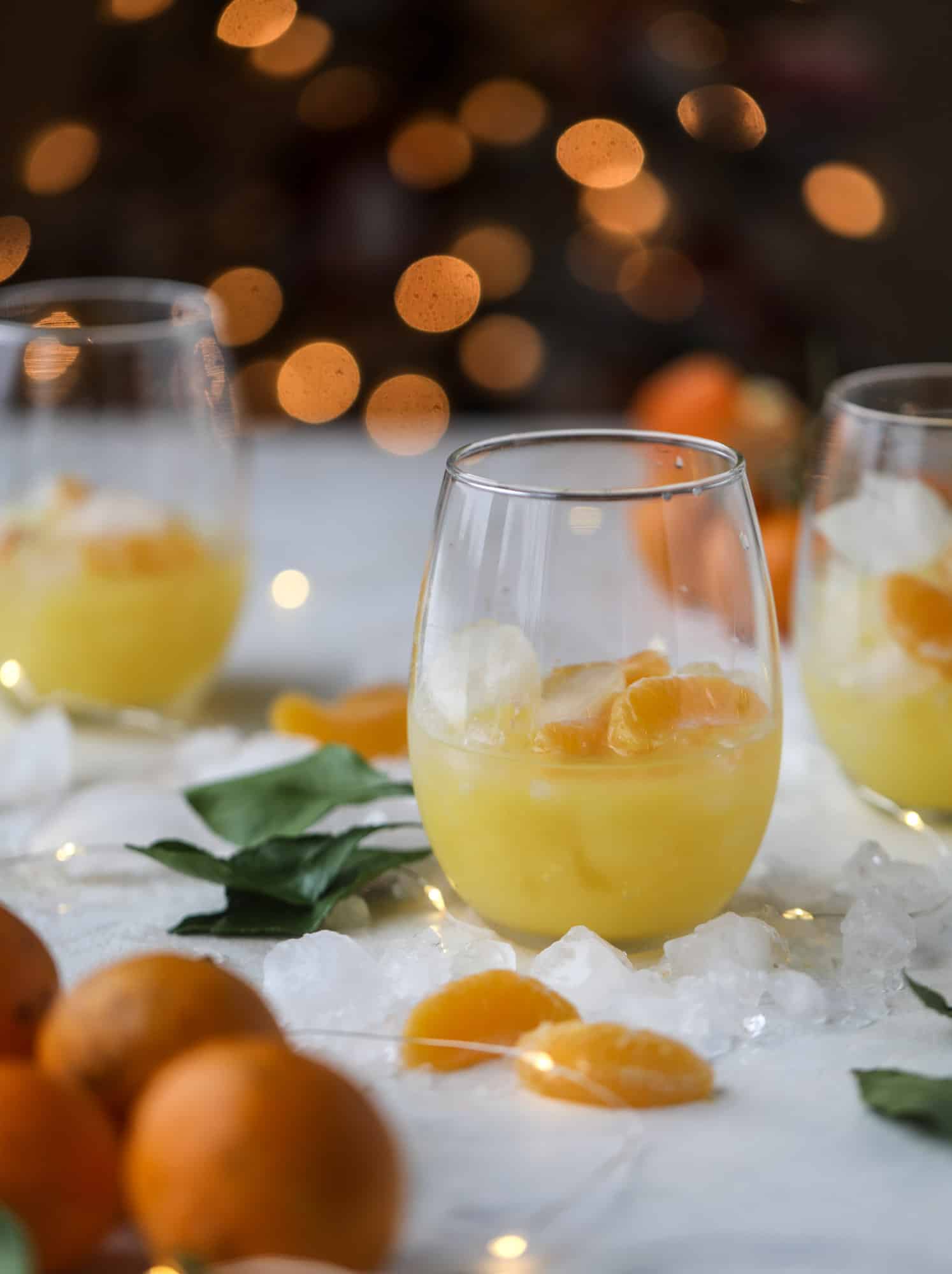 This satsuma cocktail is perfect for the holiday season and winter months when sweet satsumas are in season! This cocktail uses gin or vodka and is topped with champagne and garnished with a few satsuma wedges. Delicious! I howsweeteats.com #satsuma #cocktail
