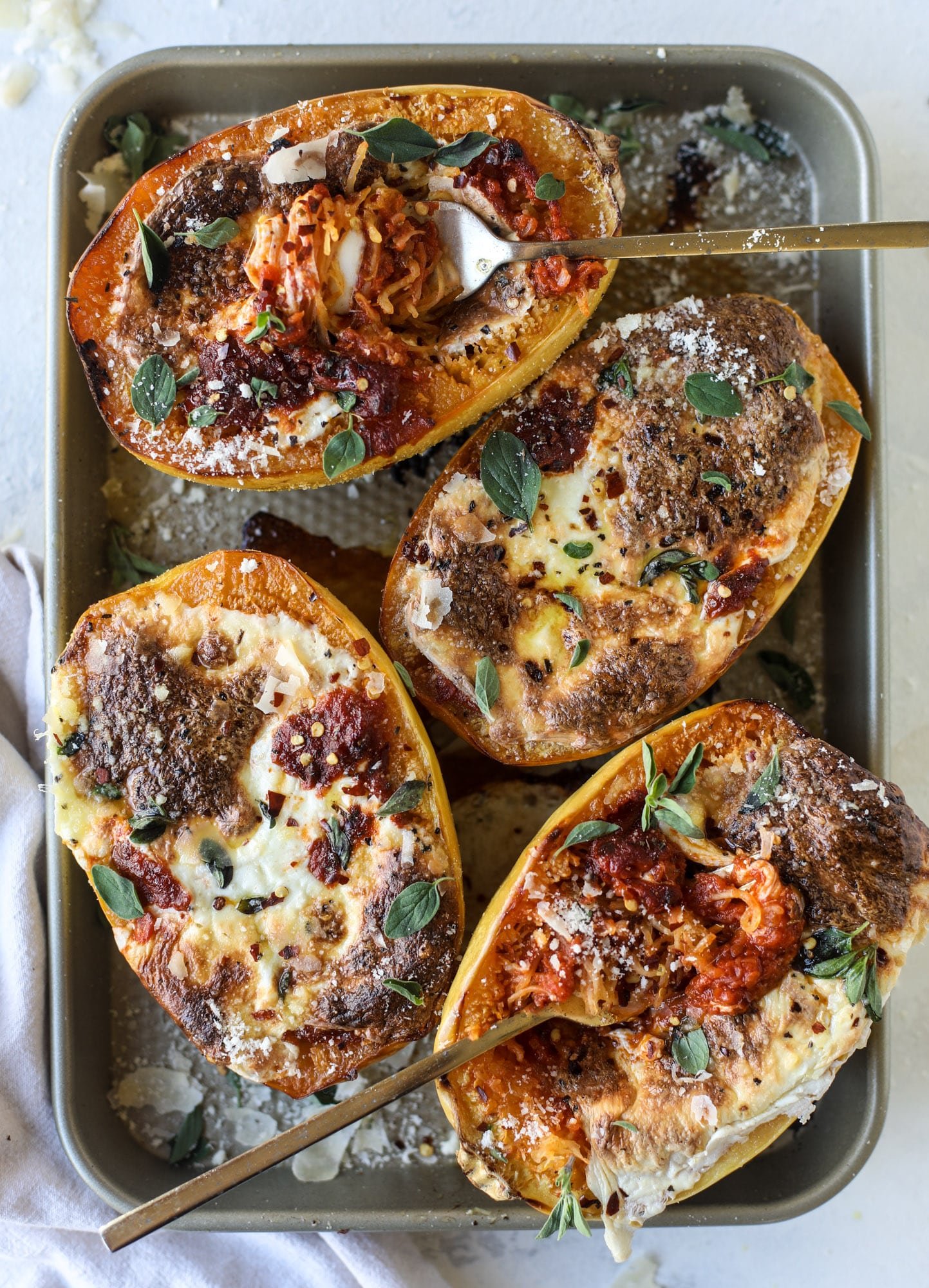 Spaghetti squash parmesan is a delicious weeknight meal! Topped with marinara or bolognese, melty cheese and fresh herbs, it's easy and delicious! I howsweeteats.com #spaghettisquash #parmesan