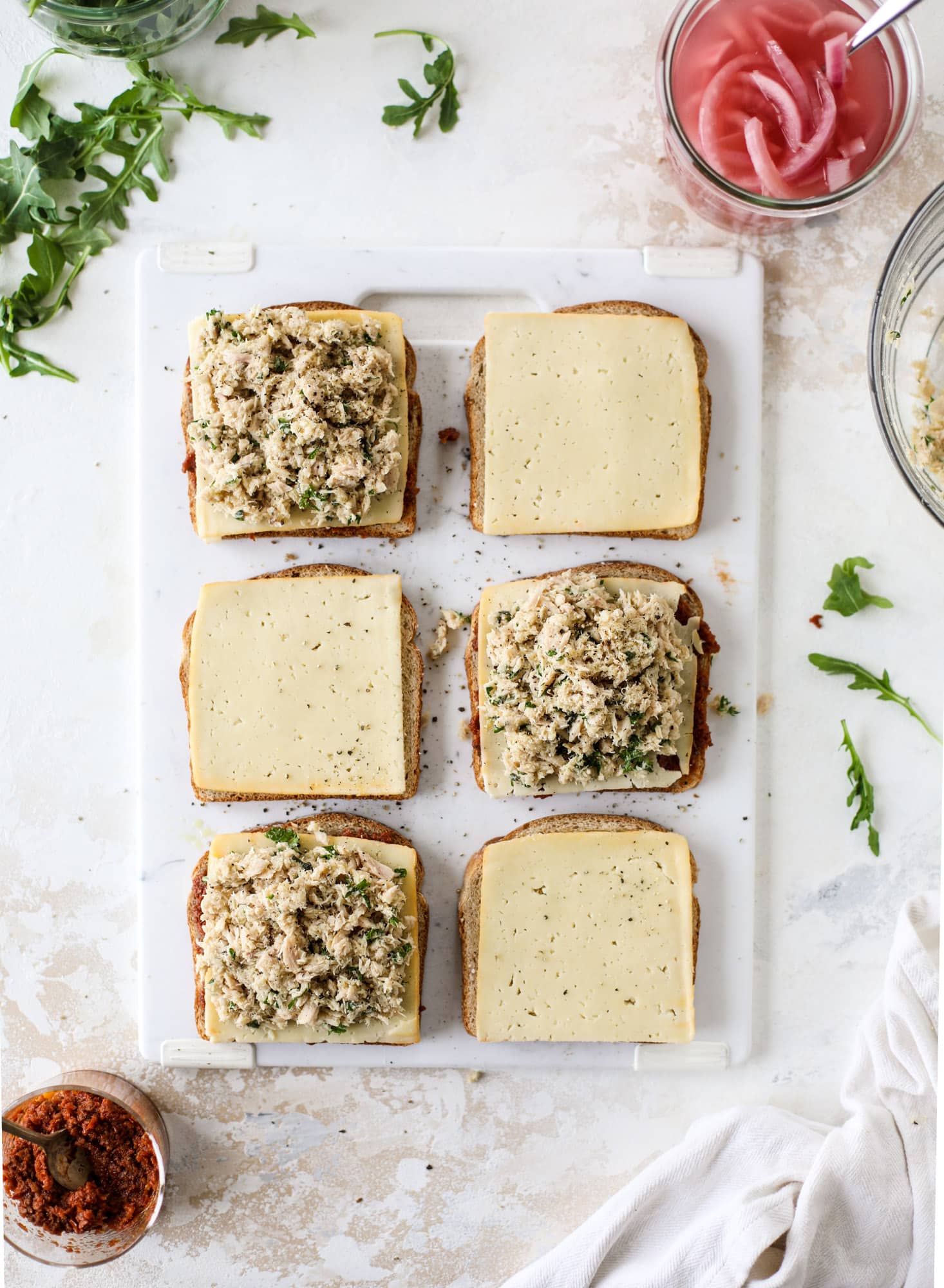This tuscan tuna melt is a modern way to enjoy a tuna sandwich, with peppery arugula, melty cheese, pickled onions and sun dried tomato spread! I howsweeteats.com #tuna #melt