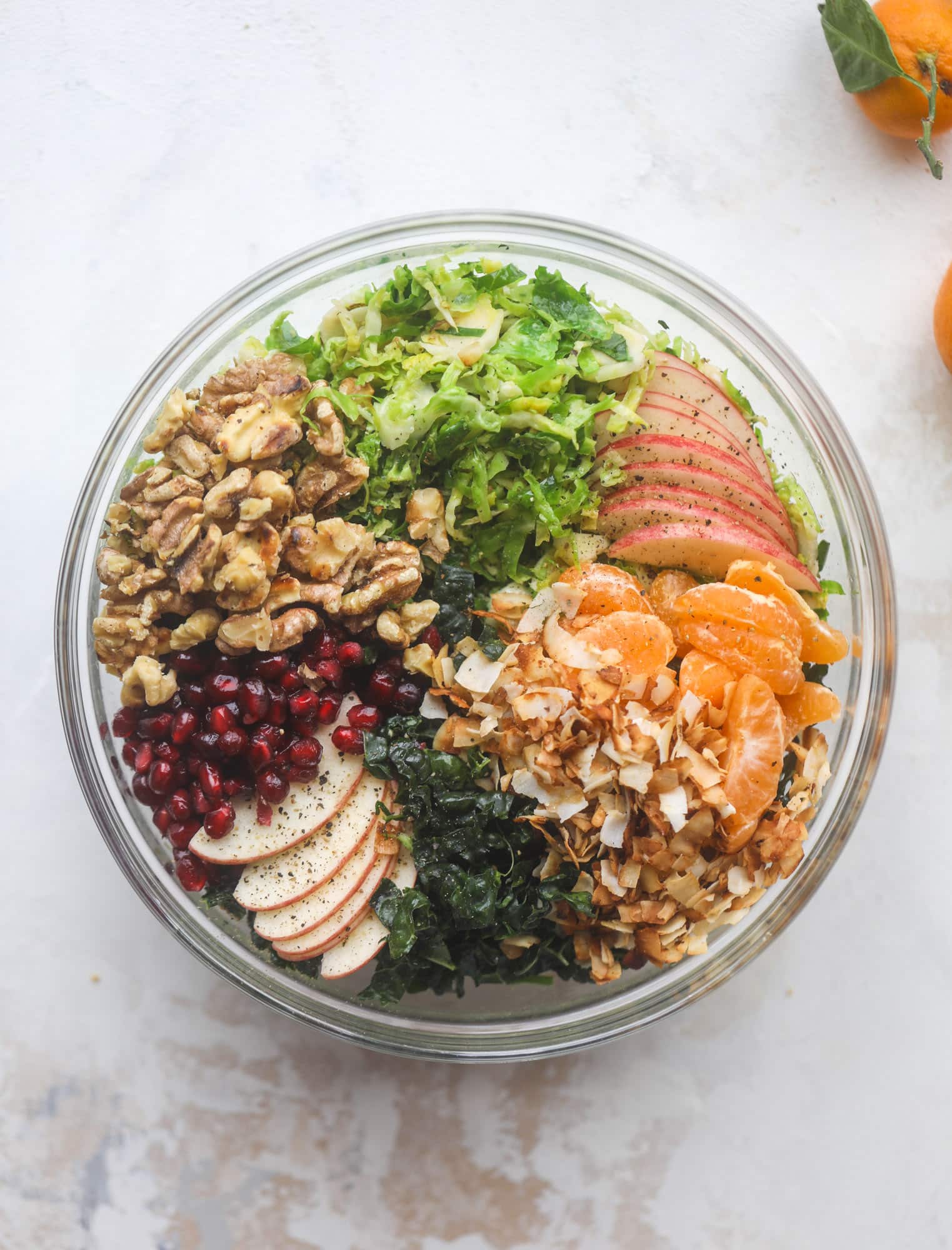 This winter crunch salad is loaded with tons of delicious, crunchy seasonal ingredients. A base of brussels sprouts and kale is topped with sliced apples, satsuma wedges, pomegranate arils, toasted walnuts and savory flaked coconut crunch. Delish! I howsweeteats.com #winter #salad