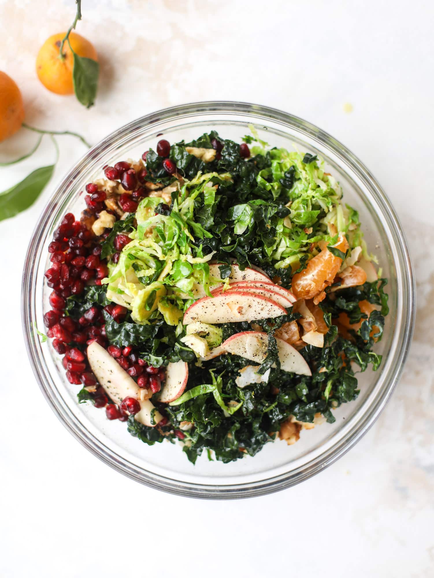 This winter crunch salad is loaded with tons of delicious, crunchy seasonal ingredients. A base of brussels sprouts and kale is topped with sliced apples, satsuma wedges, pomegranate arils, toasted walnuts and savory flaked coconut crunch. Delish! I howsweeteats.com #winter #salad