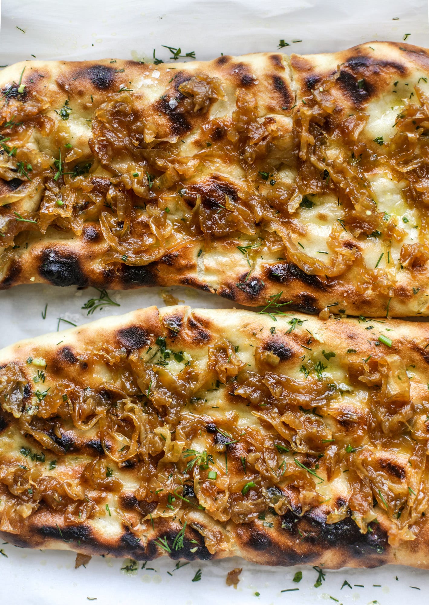 Grilled focaccia bread is such a treat! Topped with puddles of garlic butter, fresh chopped herbs and golden, caramelized onions, it's a slice of heaven.
