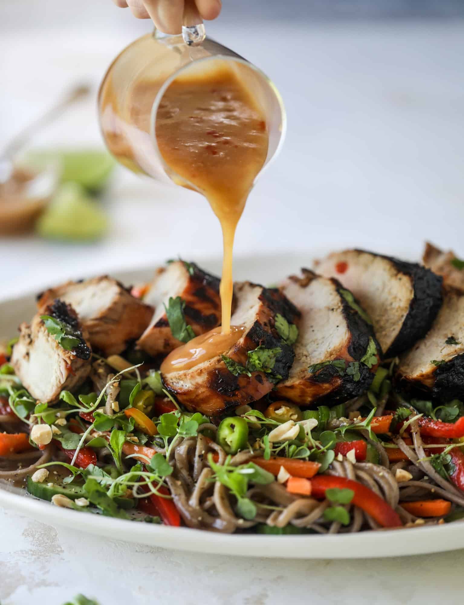 pouring peanut sauce on grilled pork tenderloin 