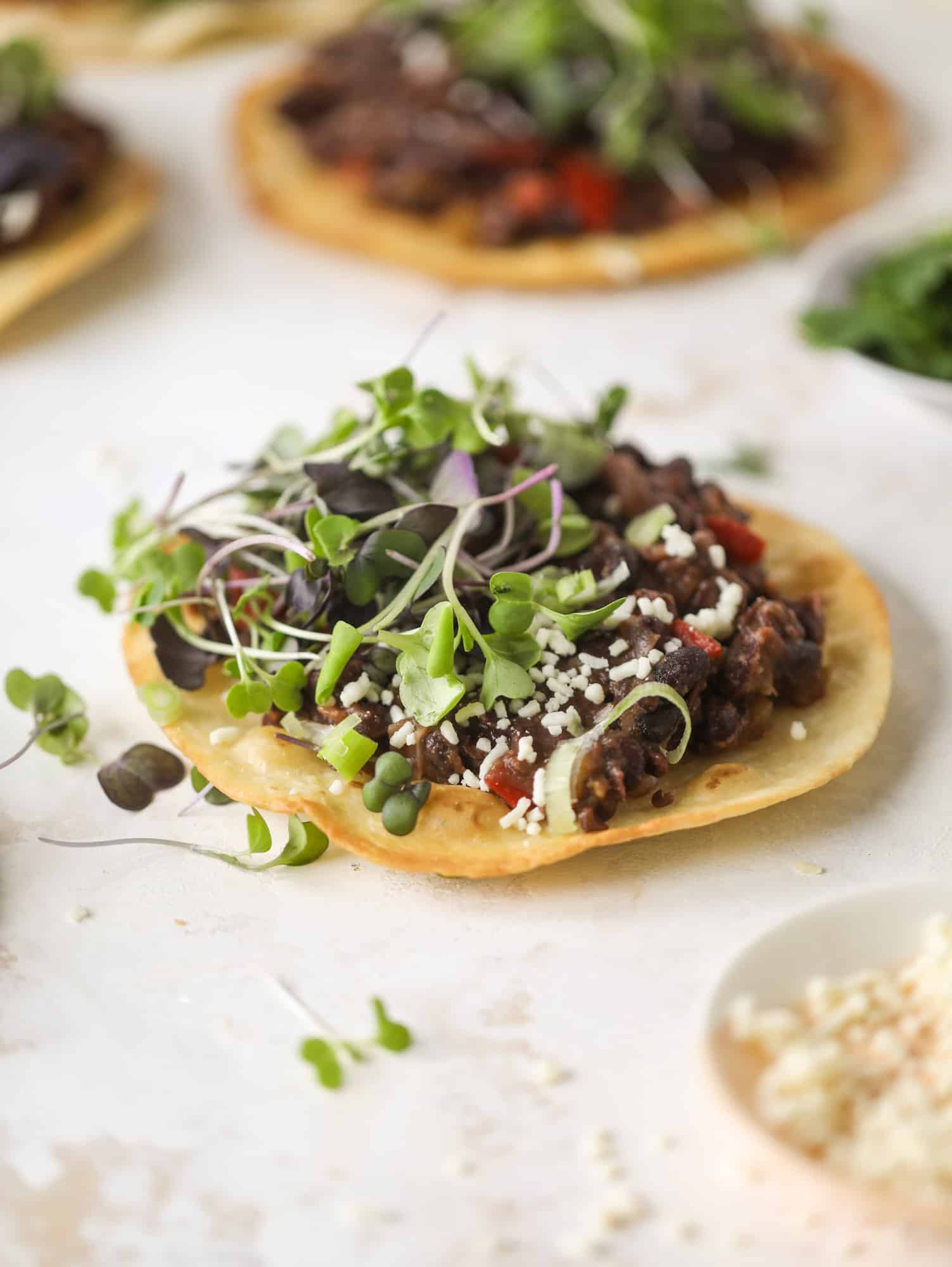 These saucy black bean tostadas are super flavorful and easy for a weeknight meal. Crunchy tortillas topped with beans and tons of veggies. Delish!