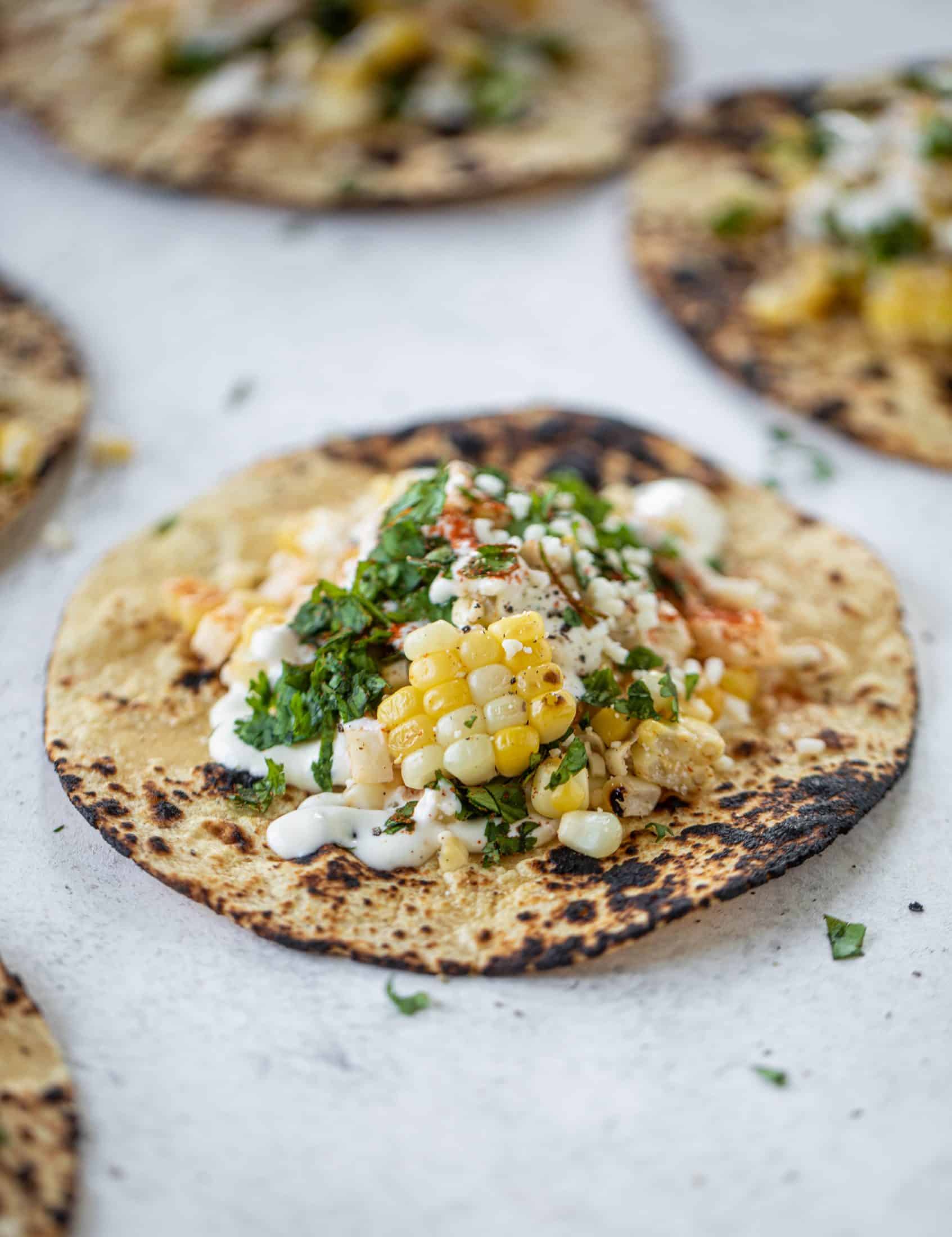 These street corn tacos are filled with a jicama corn salad and drizzled with garlic mayo. This little taco packs a major flavor punch.