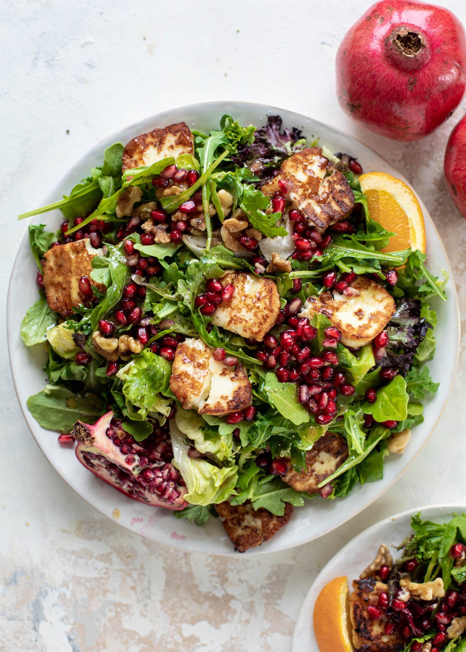 A pomegranate halloumi salad that's the perfect starter to your holiday meal! Drizzle with a spiced orange vinaigrette for the most festive flavor ever.