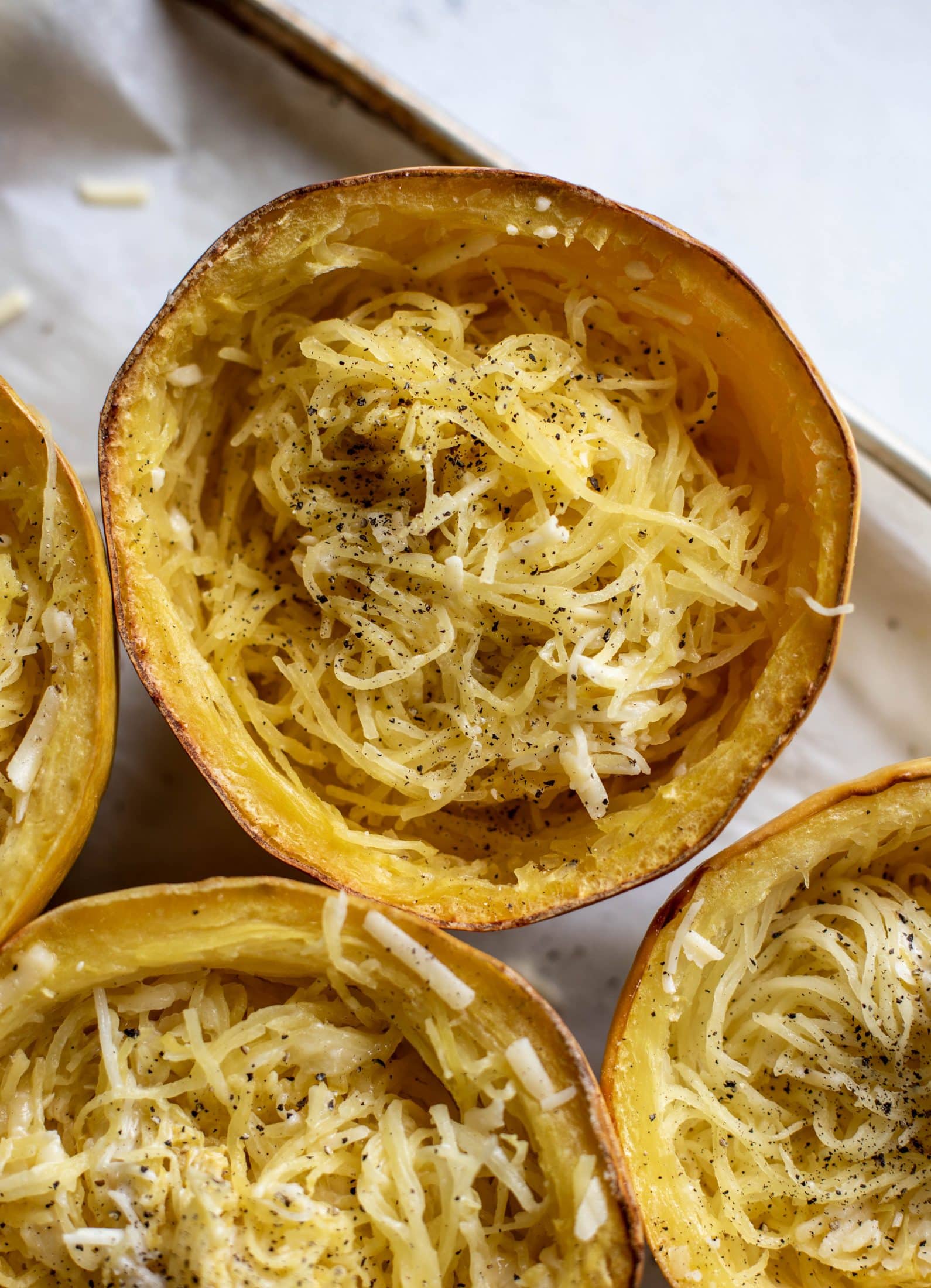 Three cheese spaghetti squash in a squash bowl! Squash tossed with fontina, gruyere and parmesan to make a creamy comforting meal.
