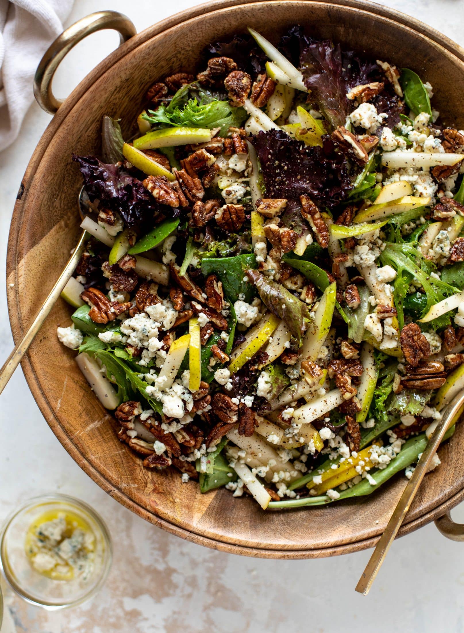 This pear gorgonzola is the perfect simple greens salad for the holiday and winter season! Topped with sweet and spicy pecans and champagne vinaigrette!
