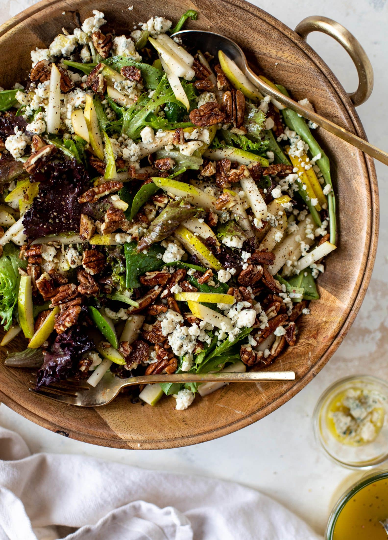 This pear gorgonzola is the perfect simple greens salad for the holiday and winter season! Topped with sweet and spicy pecans and champagne vinaigrette!