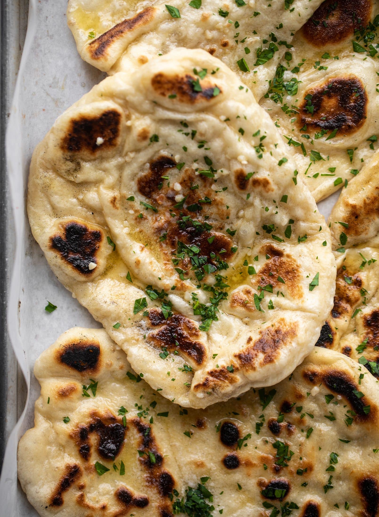 This garlic butter naan bread recipe is divine! It uses baking powder and baking soda instead of yeast and is drenched with garlic butter. So delicious!