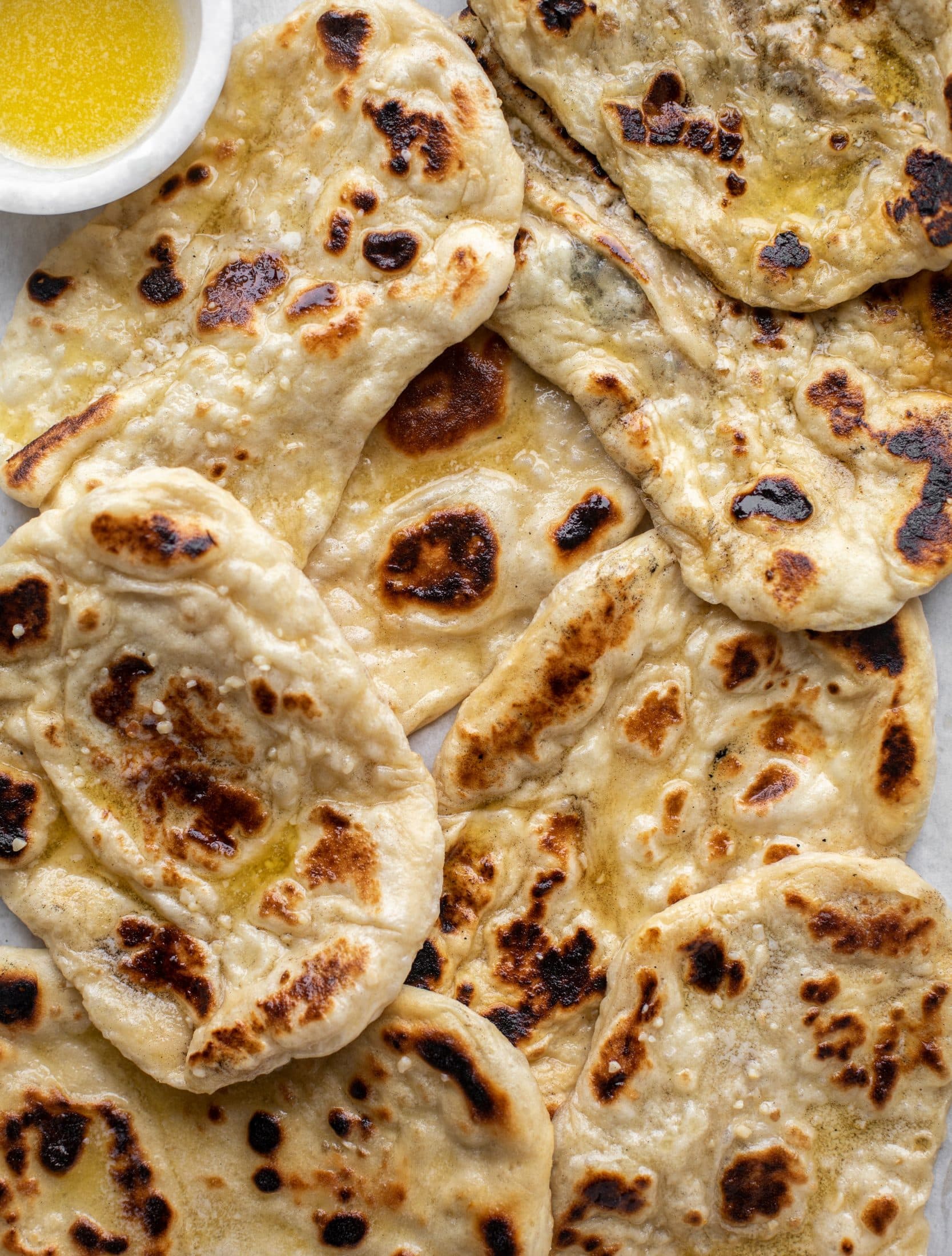 This garlic butter naan bread recipe is divine! It uses baking powder and baking soda instead of yeast and is drenched with garlic butter. So delicious!