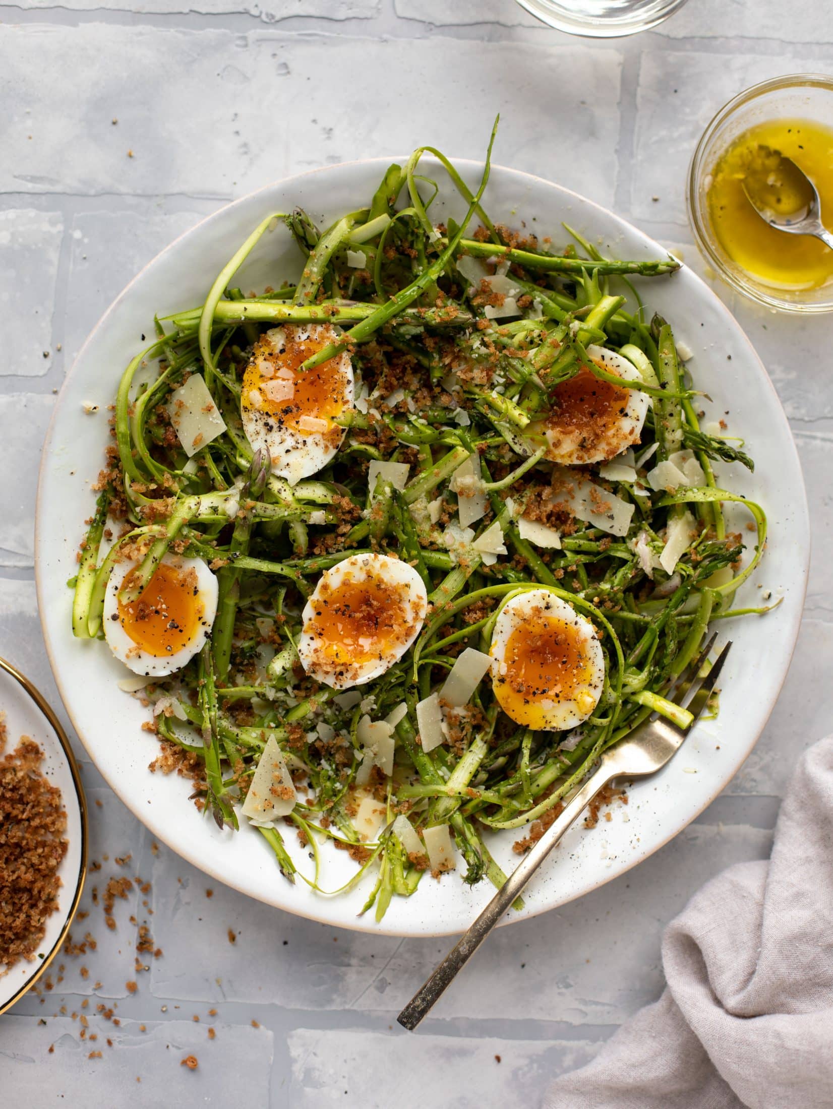 This shaved asparagus salad is tossed with a delicious parmesan vinaigrette, then topped with soft boiled eggs and finished with crunchy garlic breadcrumbs!
