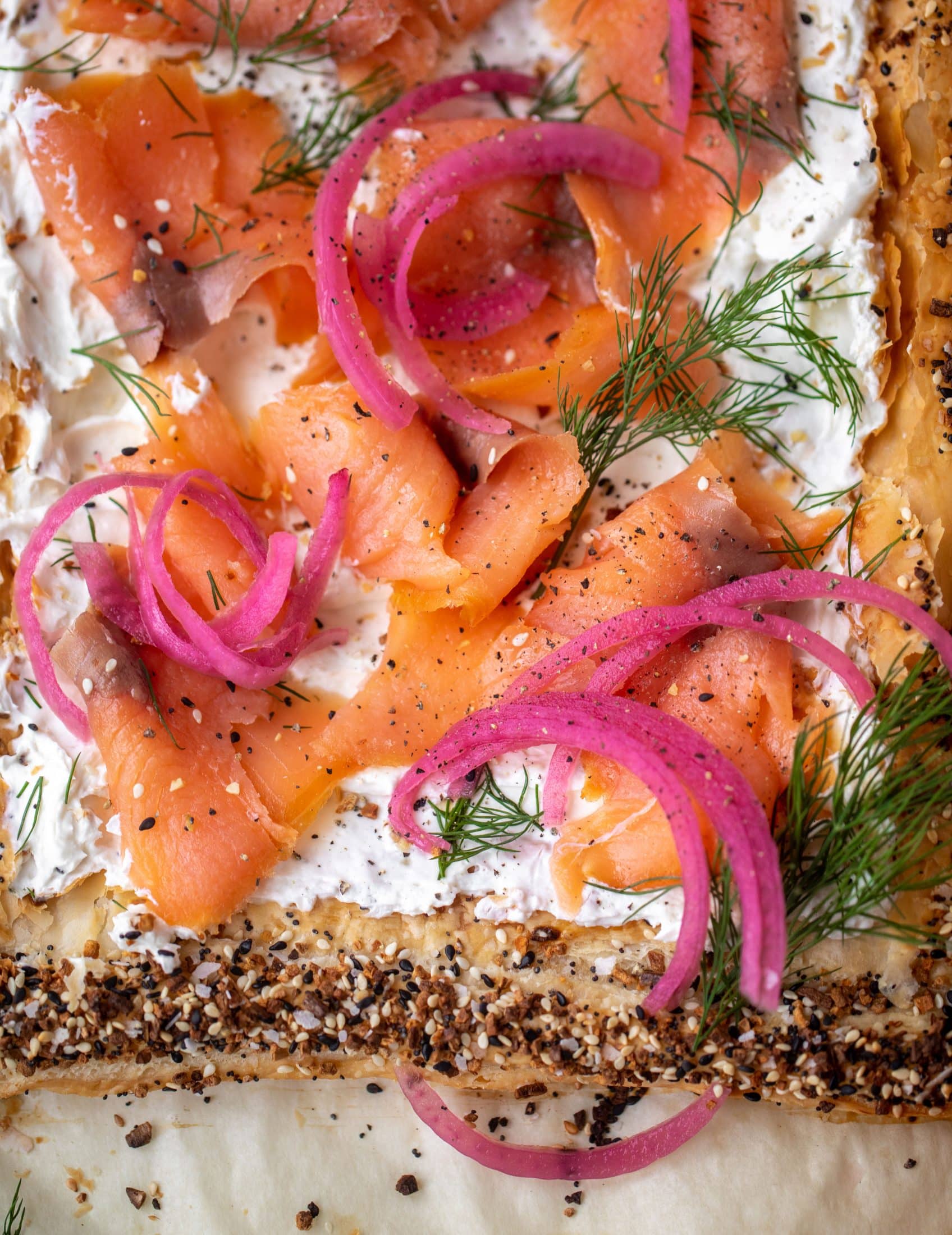 This everything smoked salmon tart is perfect for brunch! Puff pastry sprinkled with everything seasoning, slathered in cream cheese and topped with salmon.