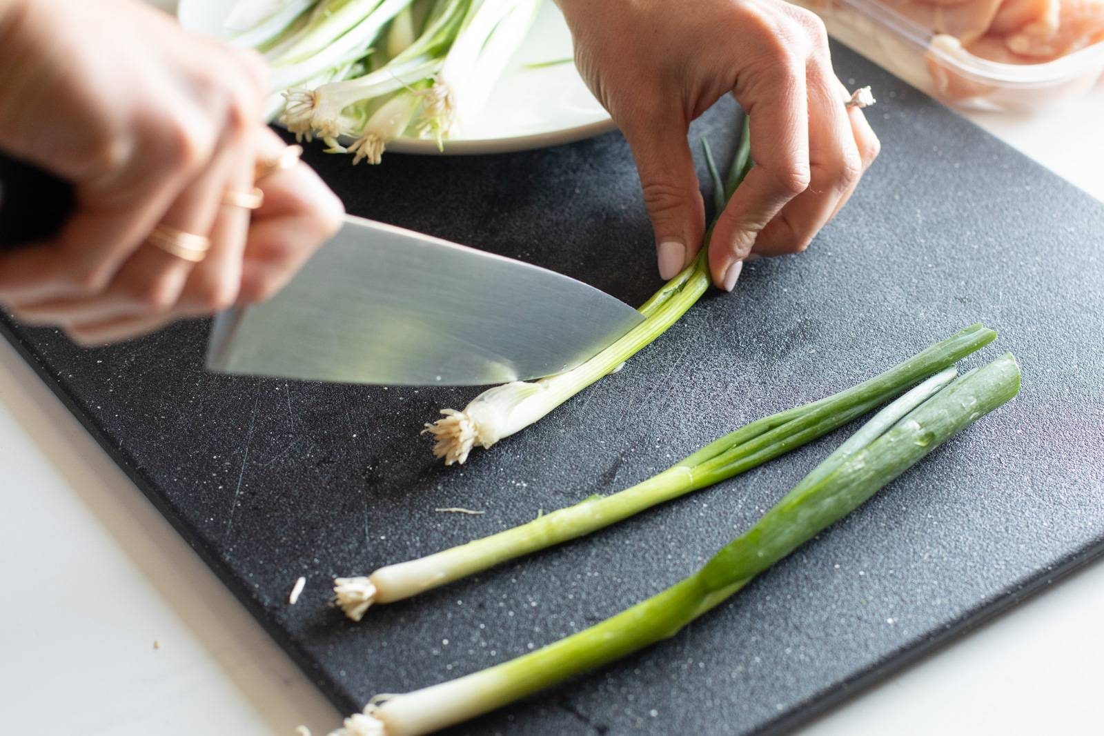 Slicing scallions on a cutting board.
