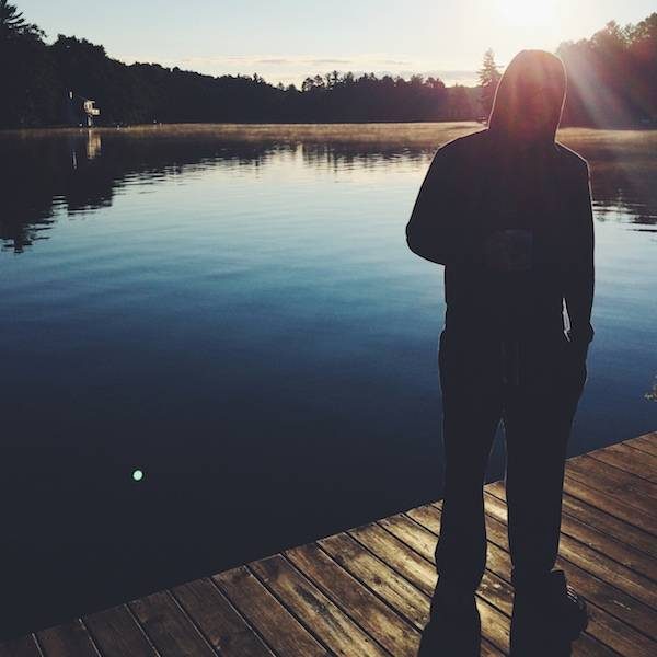 Man standing on a dock by the lake.