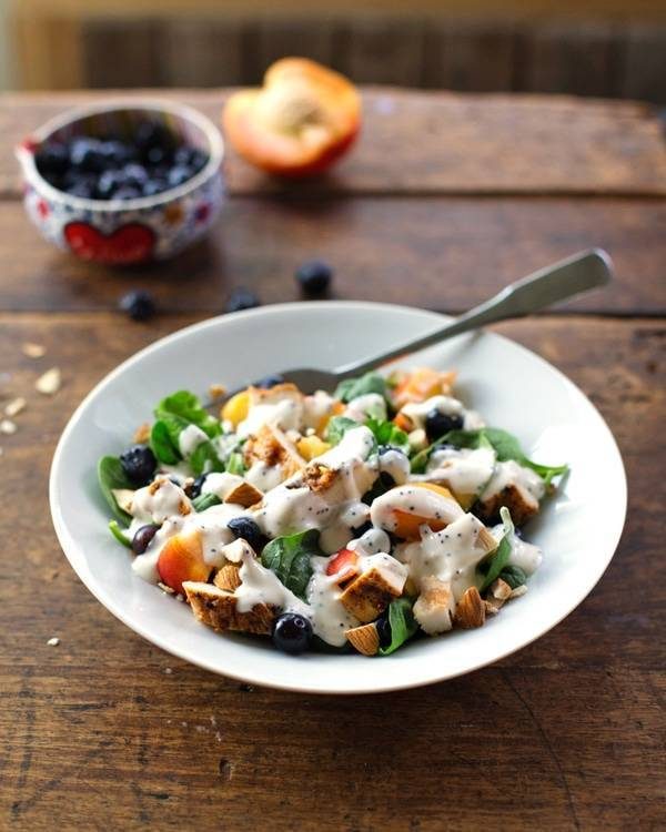Chicken and nectarine poppy seed salad in a bowl with a spoon.