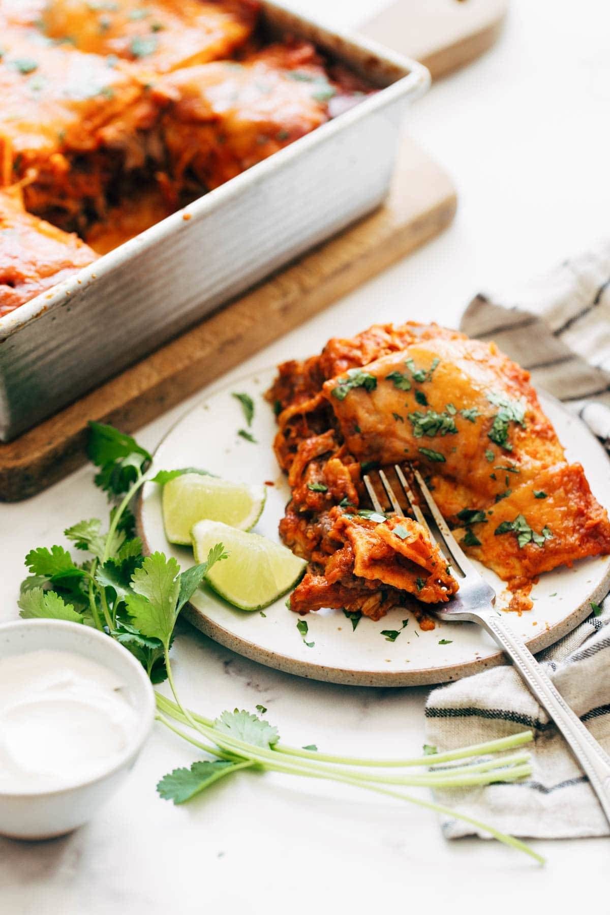 Slice of enchilada casserole on a plate with a fork.