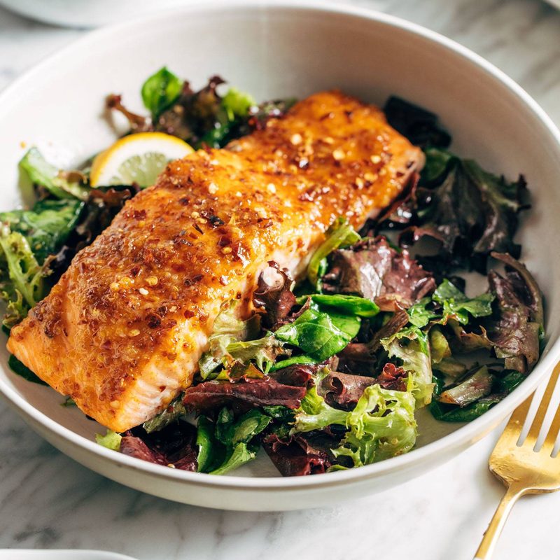 A piece of salmon sitting on a bed of greens.