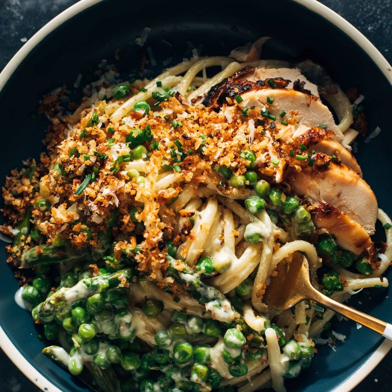 Bucatini pasta in a bowl with a fork and peas