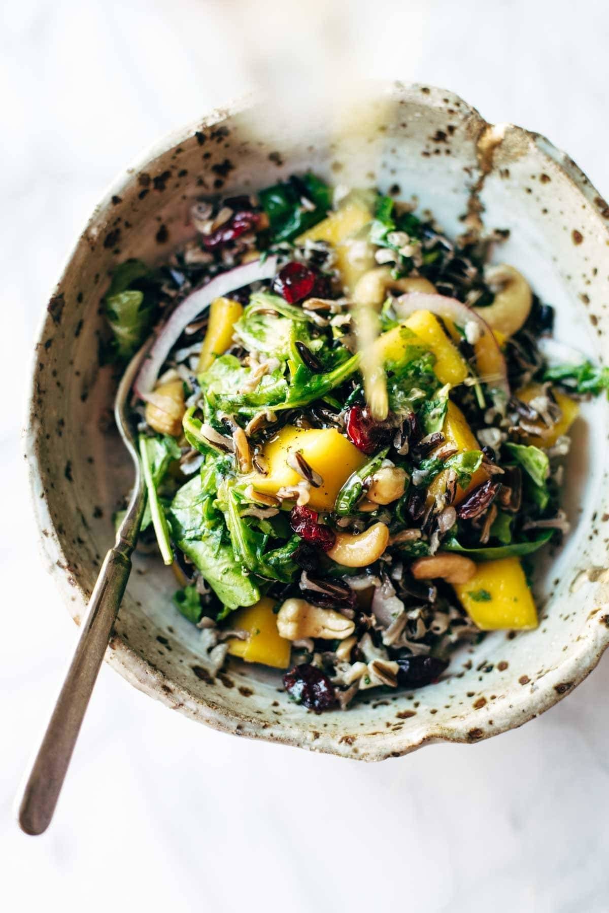 Easy Thanksgiving Salad - arugula, wild rice, cashews, dried cranberries, red onions, and a lemon dressing that shakes up easily in a jar. | pinchofyum.com